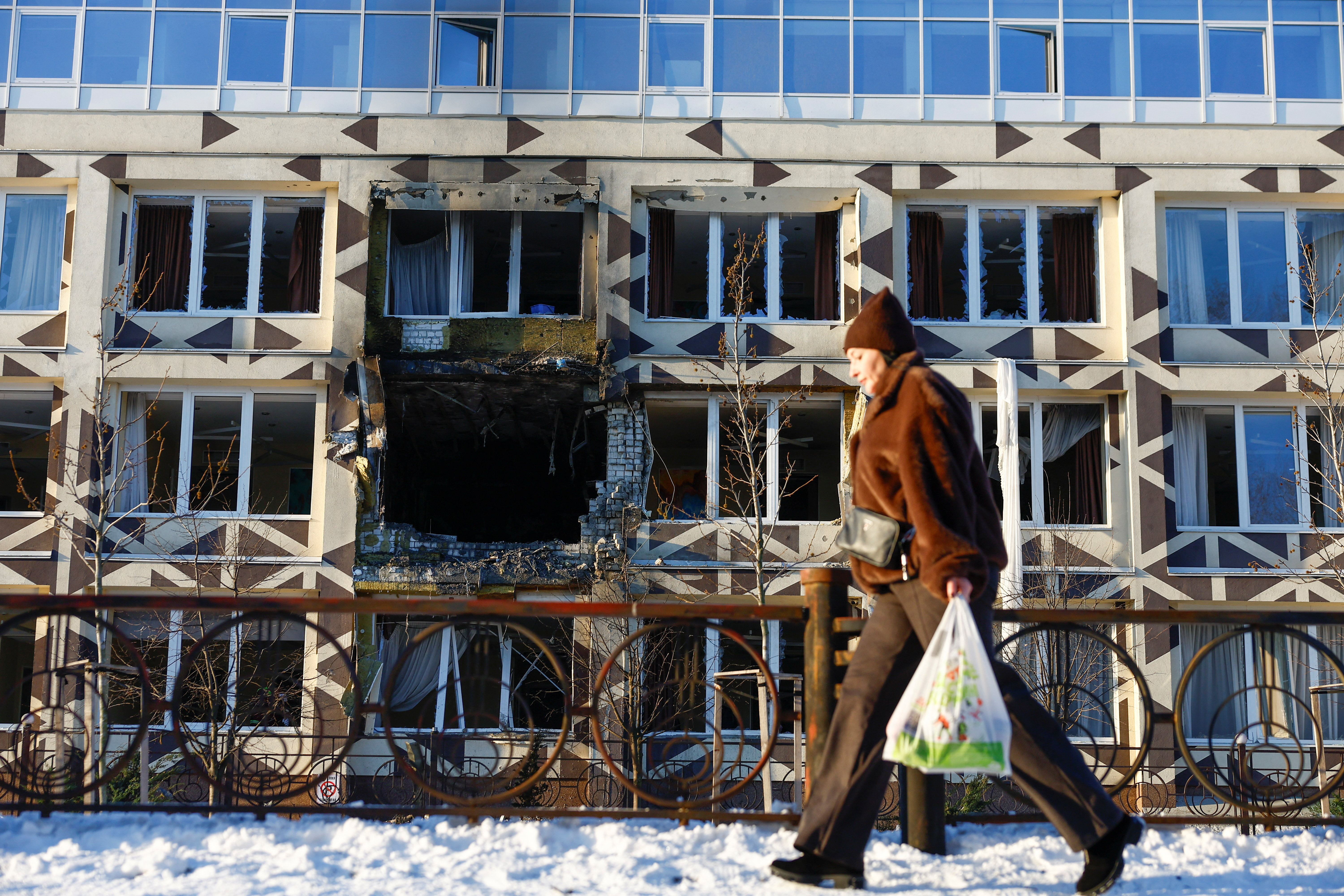 A resident walks past a damaged building.