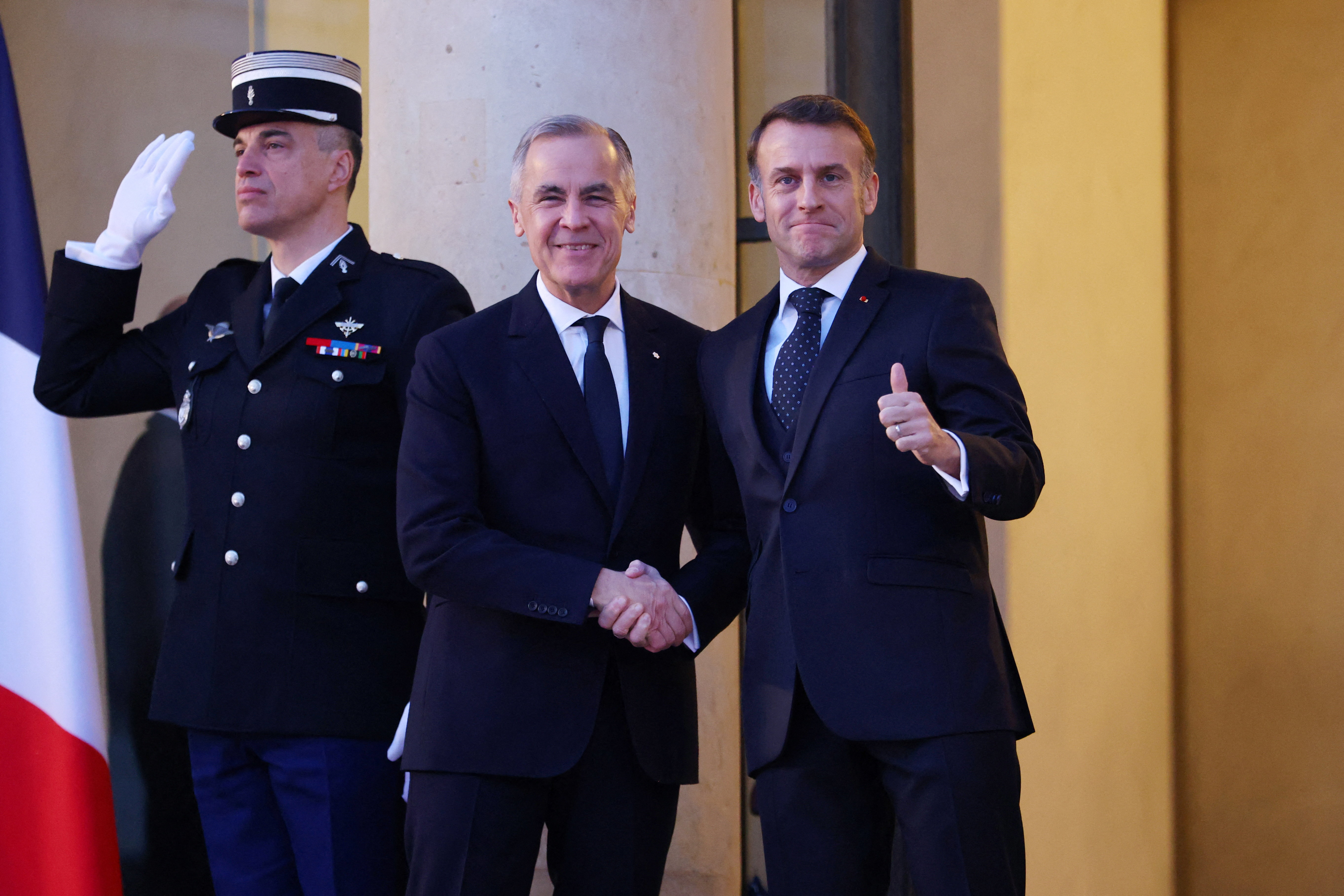 French President Emmanuel Macron shakes hands with Canada's Prime Minister Mark Carney as both pose for a photo in Paris.