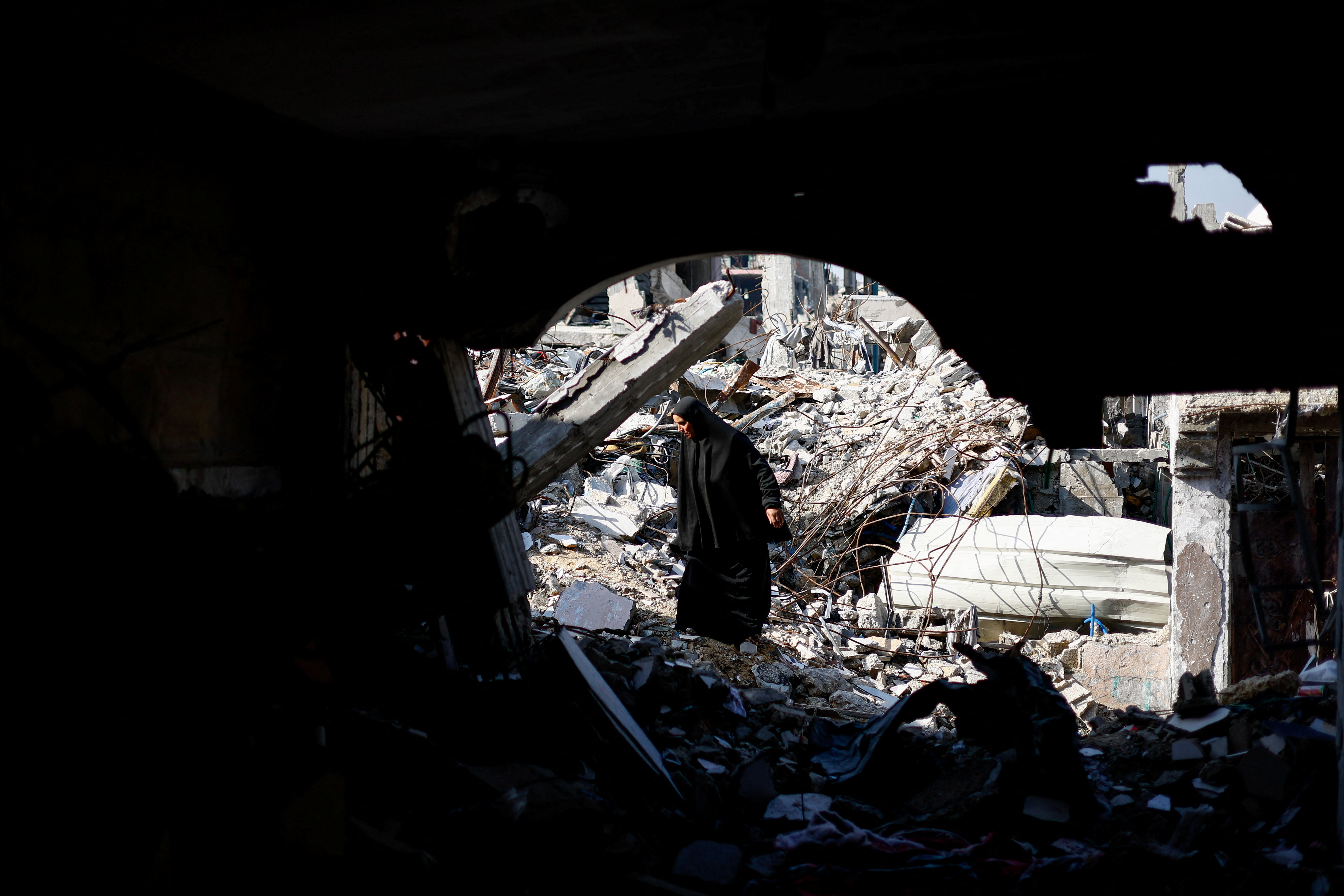 A Palestinian woman stands among rubble of residential buildings destroyed during the war, in Jabalia, northern Gaza Strip