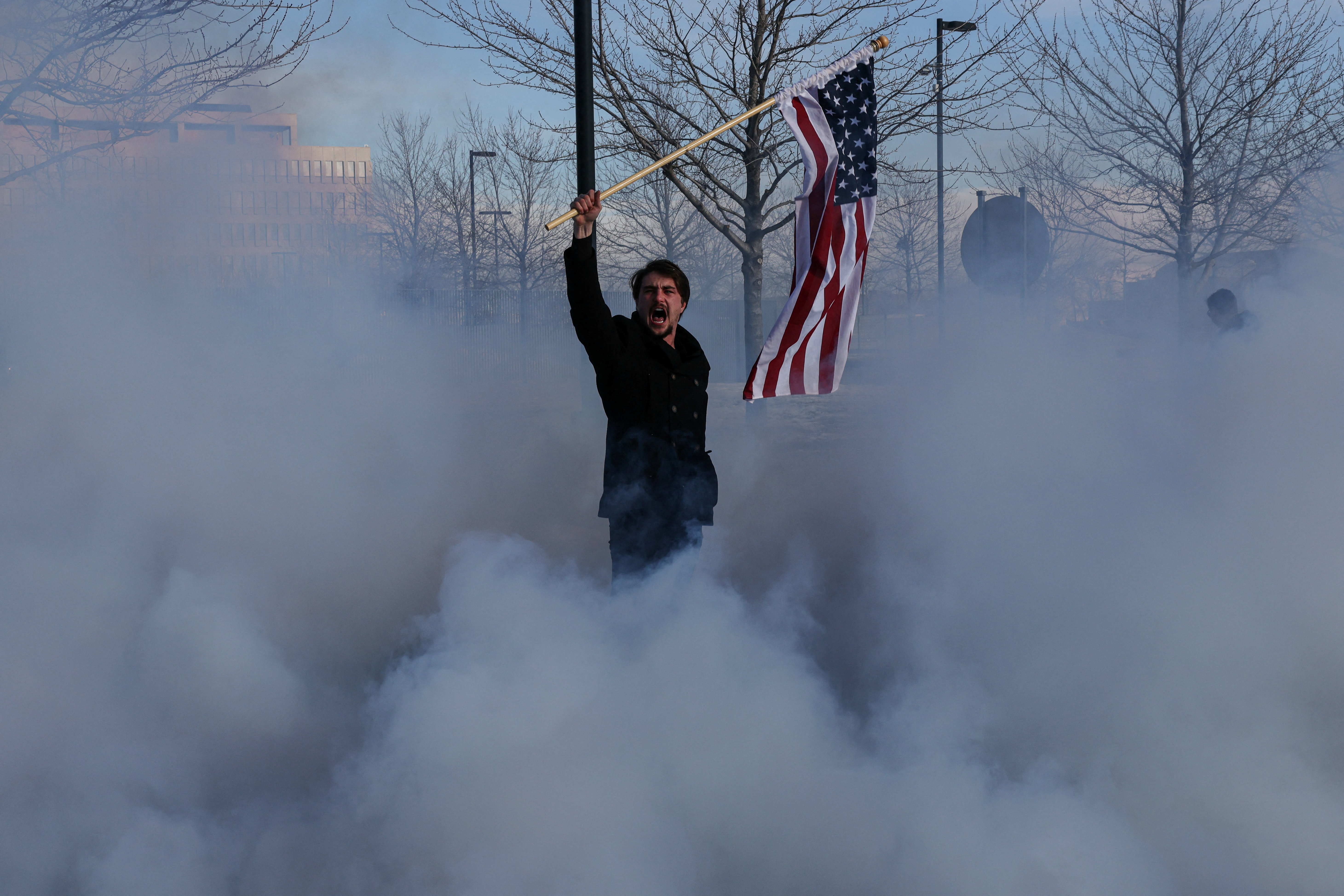 A supporter of U.S. Immigration and Customs Enforcement (ICE) waves a U.S. flag amid tear gas, after clashes with demonstrators protesting increased immigration enforcement and the fatal shooting of Renee Nicole Good by an ICE agent, in Minneapolis, Minnesota, U.S.,