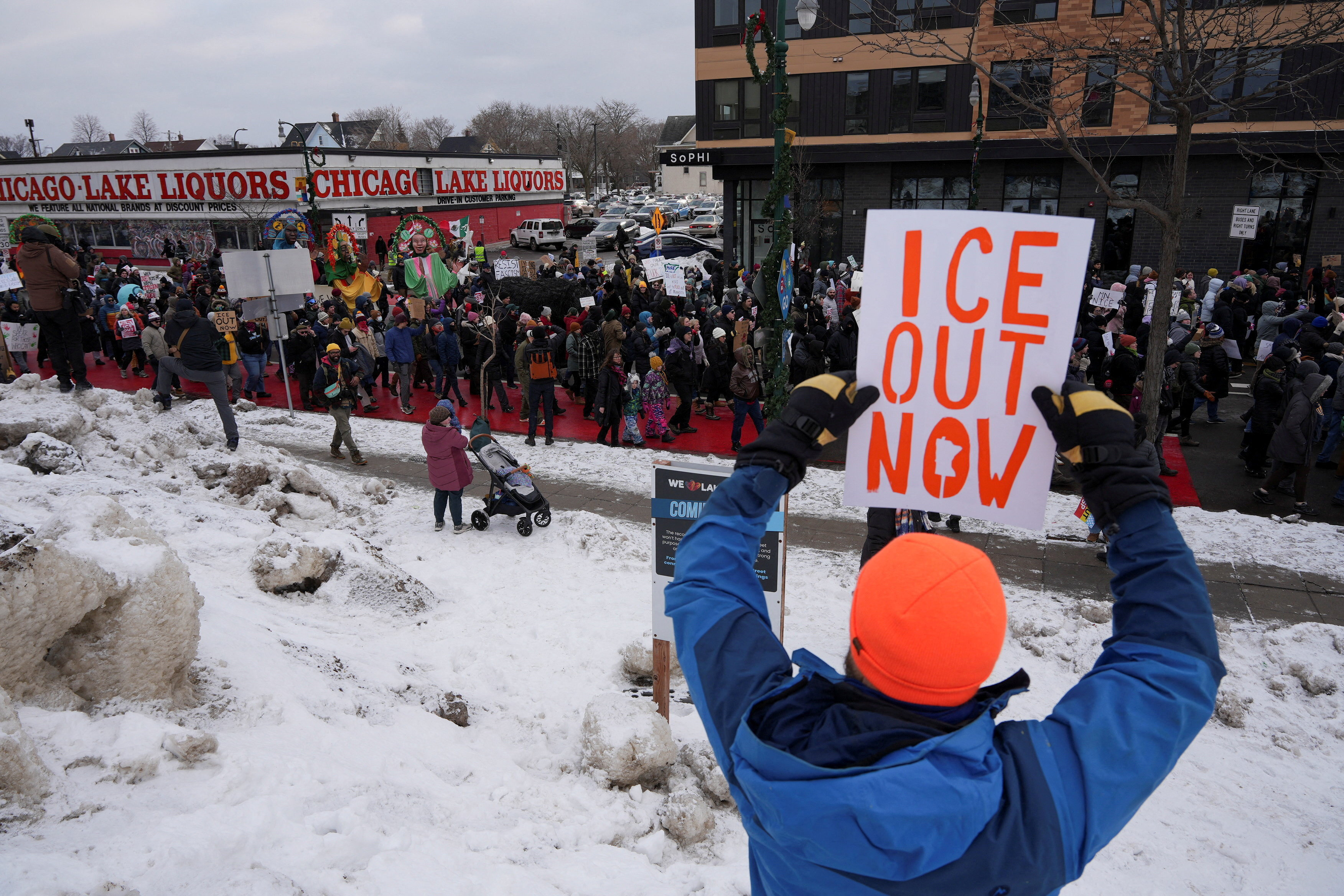 A protester lifts a sign that reads, "ICE out now"