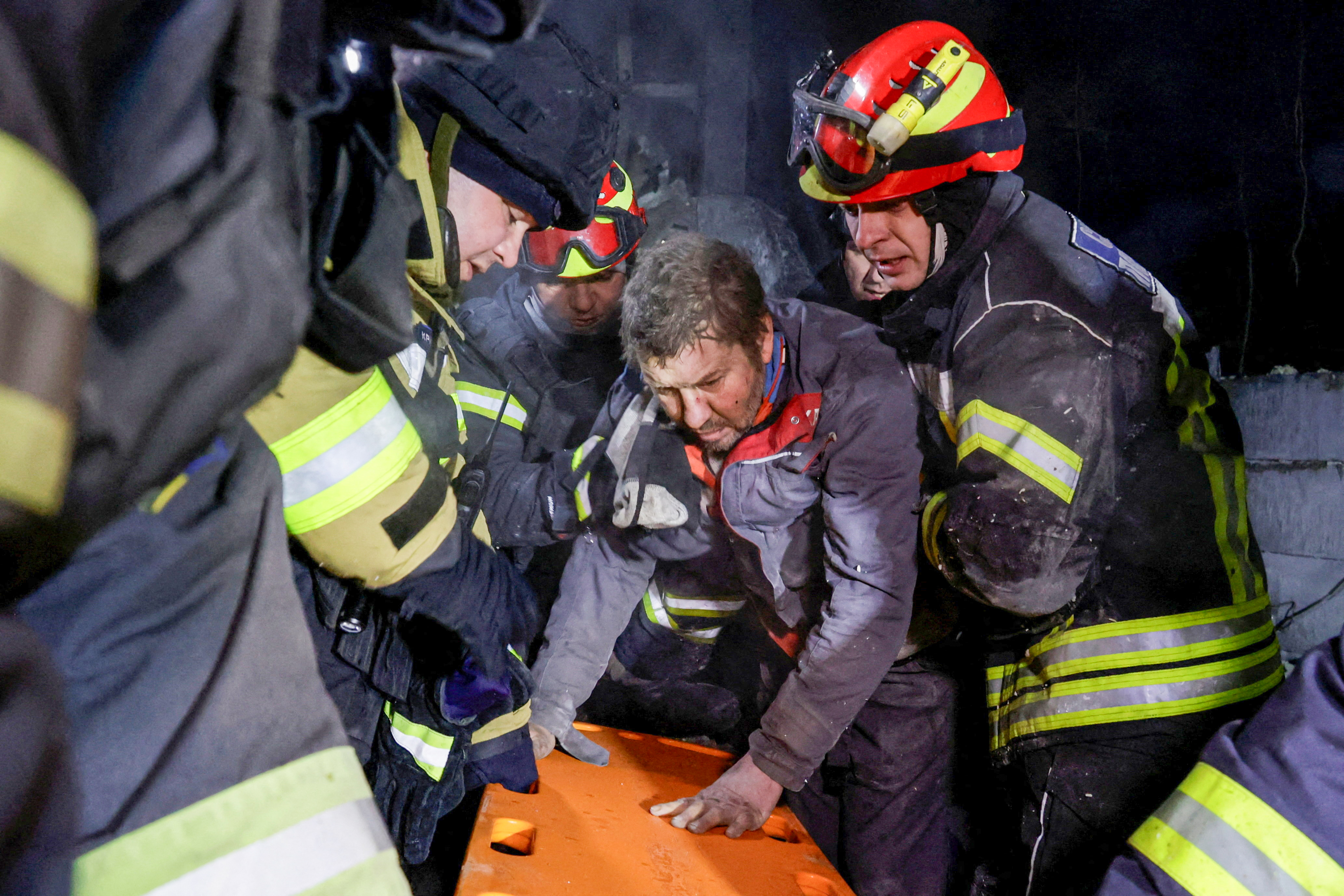 Rescuers assist a man after they rescued him from debris at the site of a logistics hub of a private delivery company hit by Russian missile strikes, amid Russia's attack on Ukraine, in Kharkiv, Ukraine January 13, 2026. REUTERS/Sofiia Gatilova TPX IMAGES OF THE DAY