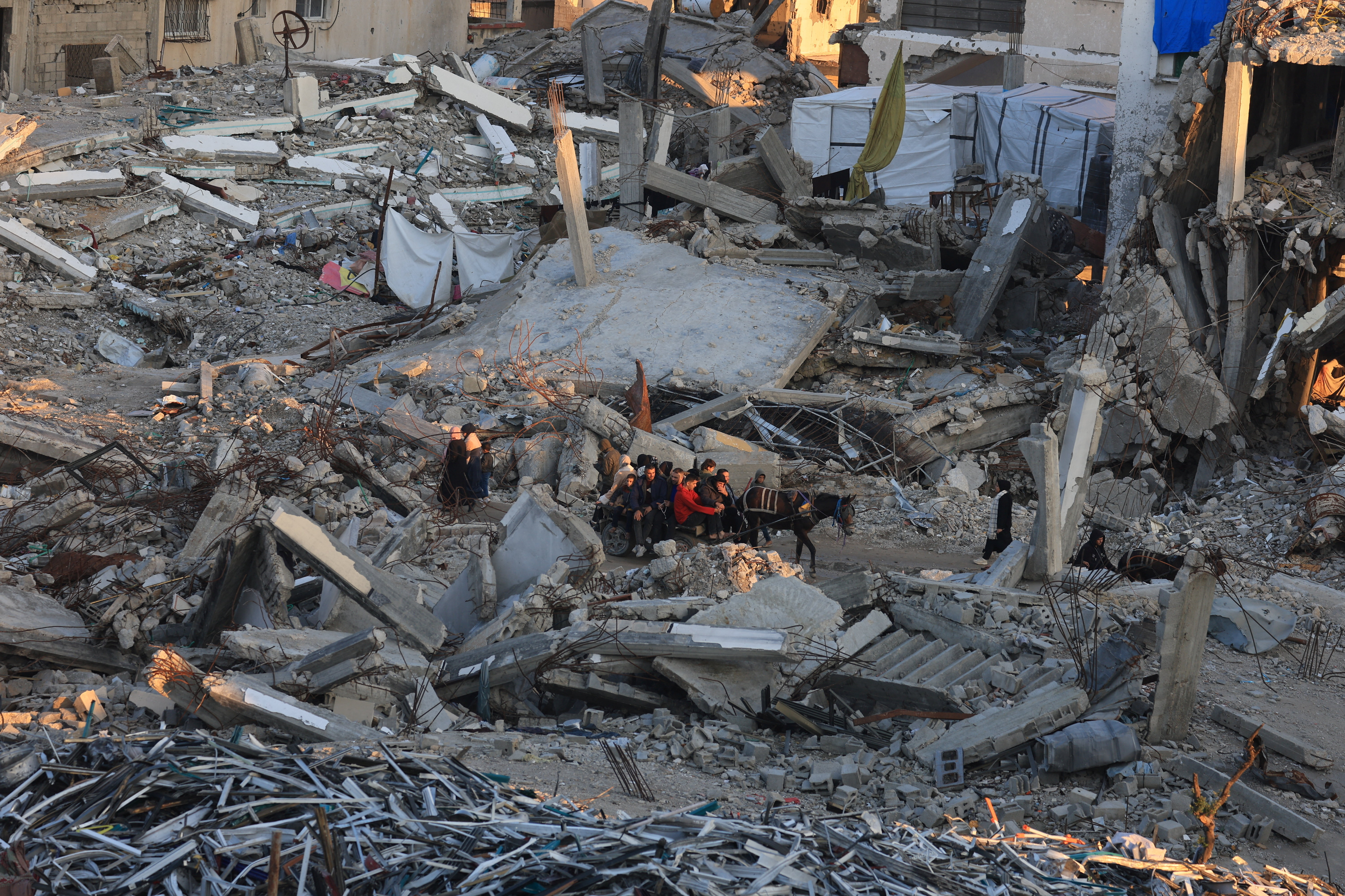 Palestinians move past the rubble of residential buildings destroyed during the war,