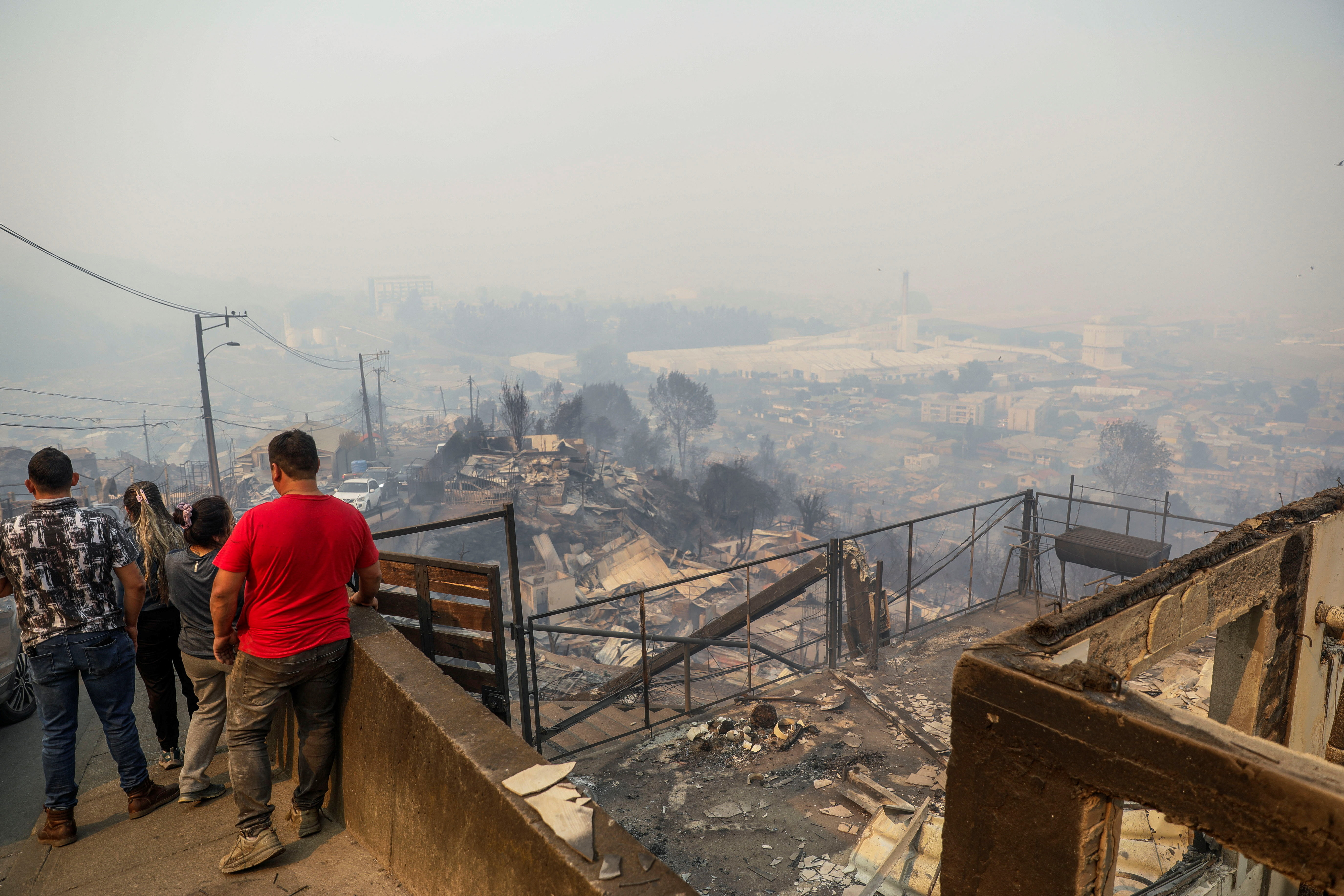 People stand outside damaged buildings in the aftermath of a forest fire in the Biobio region where, according to local media, multiple wildfires prompted emergency evacuations, in Concepcion, Chile, January 18, 2026. REUTERS/Juan Gonzalez