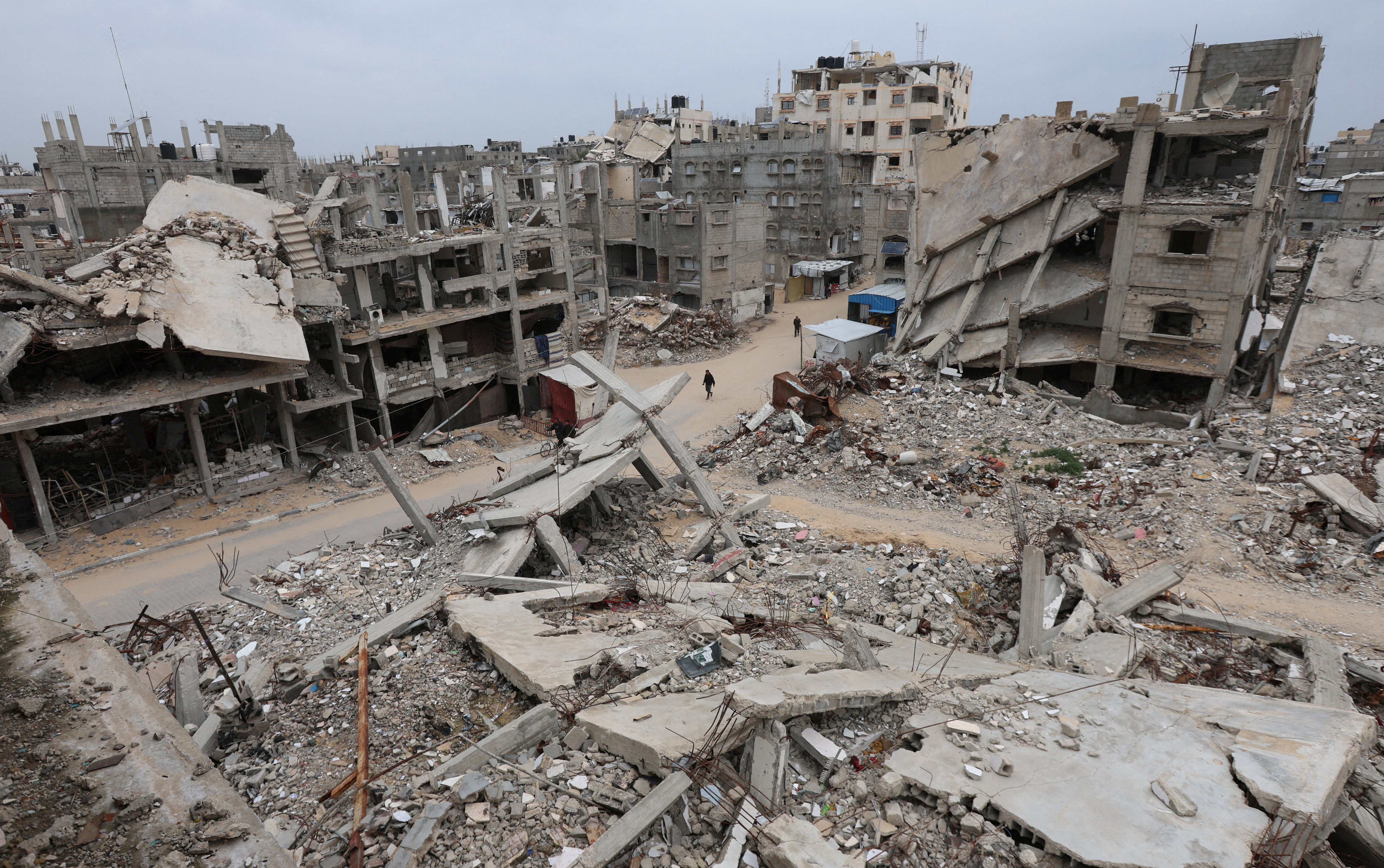 FILE PHOTO: Palestinians walk surrounded by the rubble of houses destroyed in Israeli strikes during the war, in Khan Younis, southern Gaza Strip,