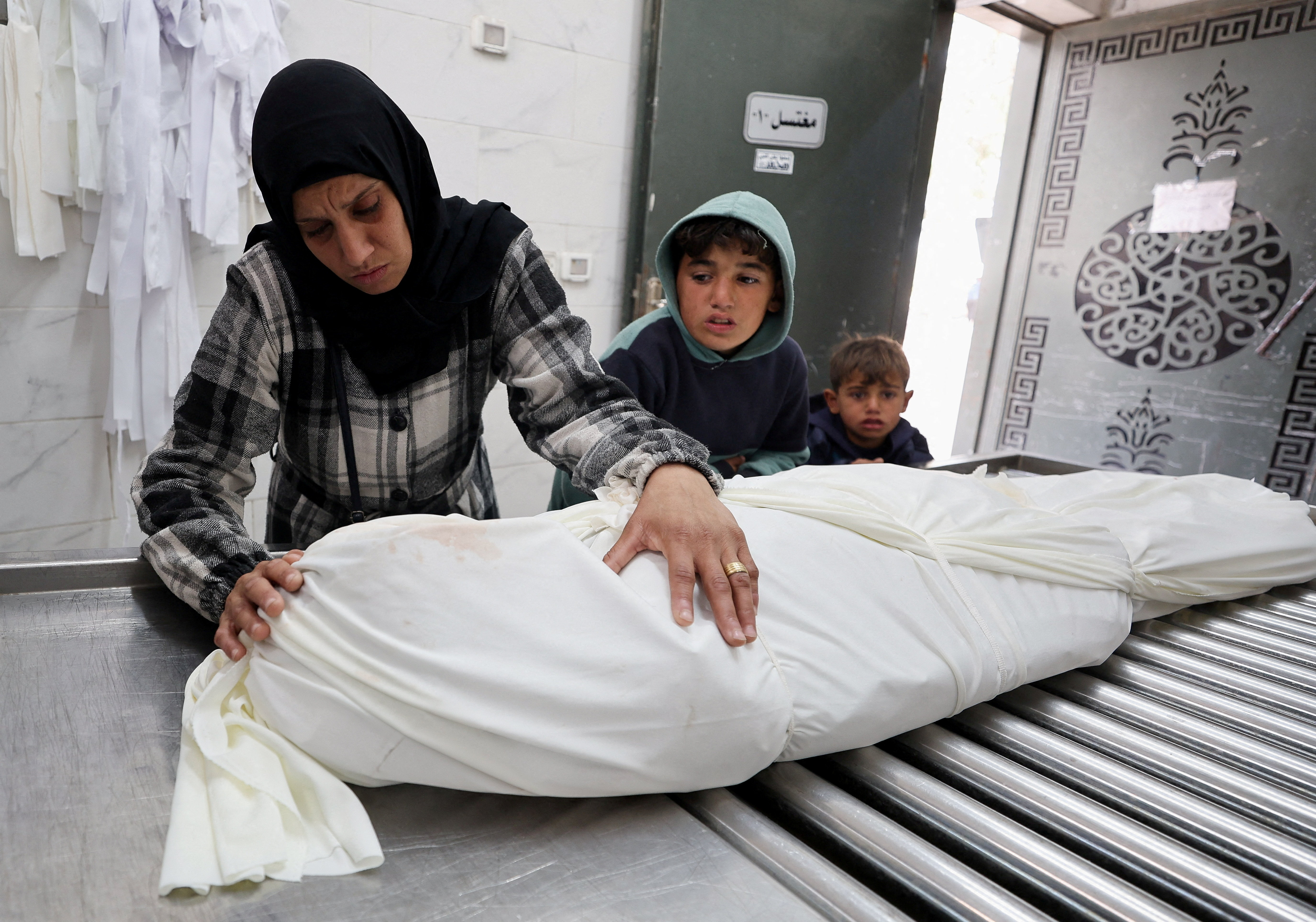 A mourner and children react next to a body during the funeral of Palestinians who, according to medics, were killed by Israeli strikes on Saturday, at Al-Shifa Hospital in Gaza, January 24, 2026. REUTERS/Dawoud Abu Alkas TPX IMAGES OF THE DAY