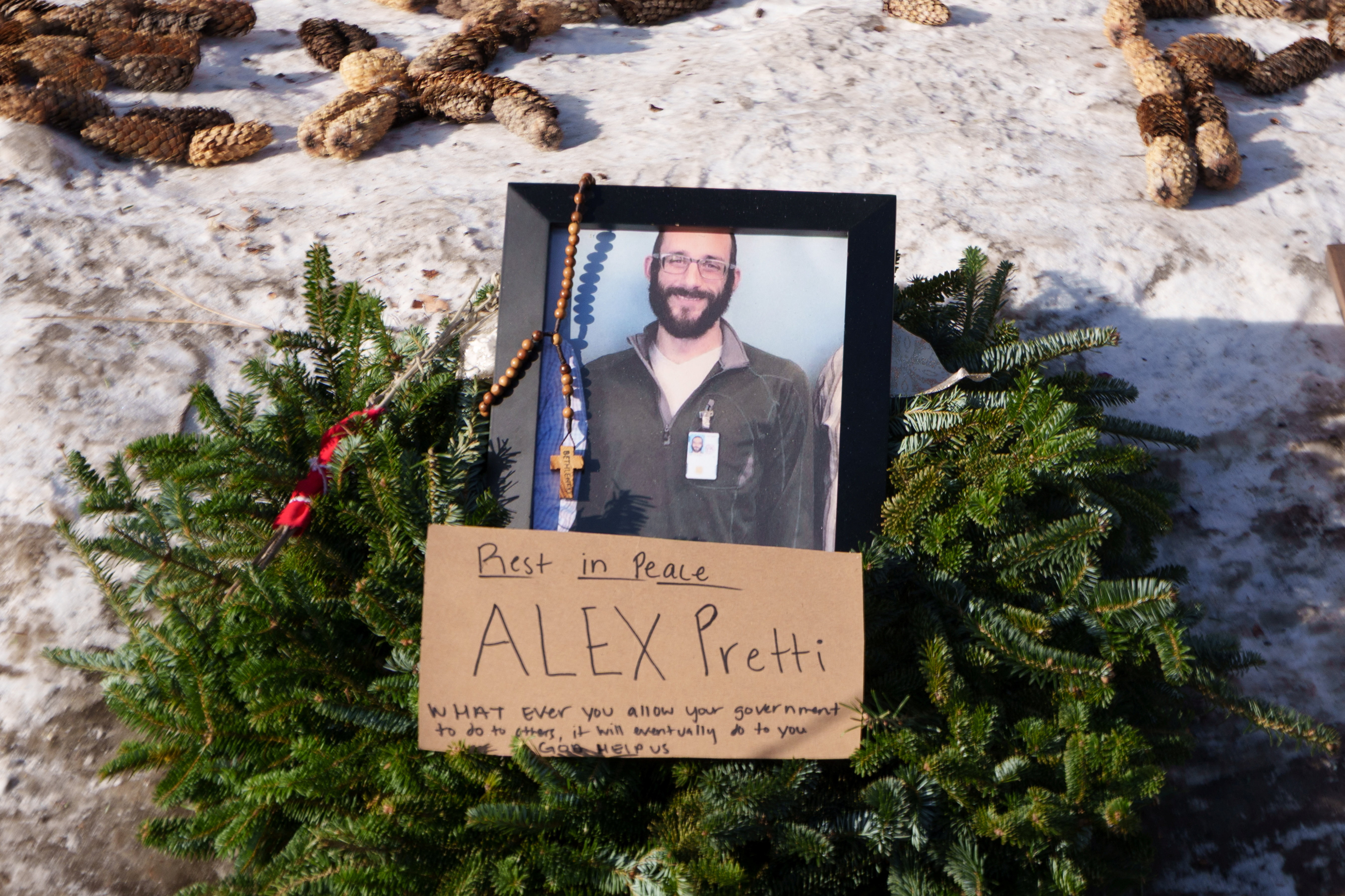 A wreath surrounds an image of Alex Pretti at a makeshift memorial near the site where he was fatally shot.