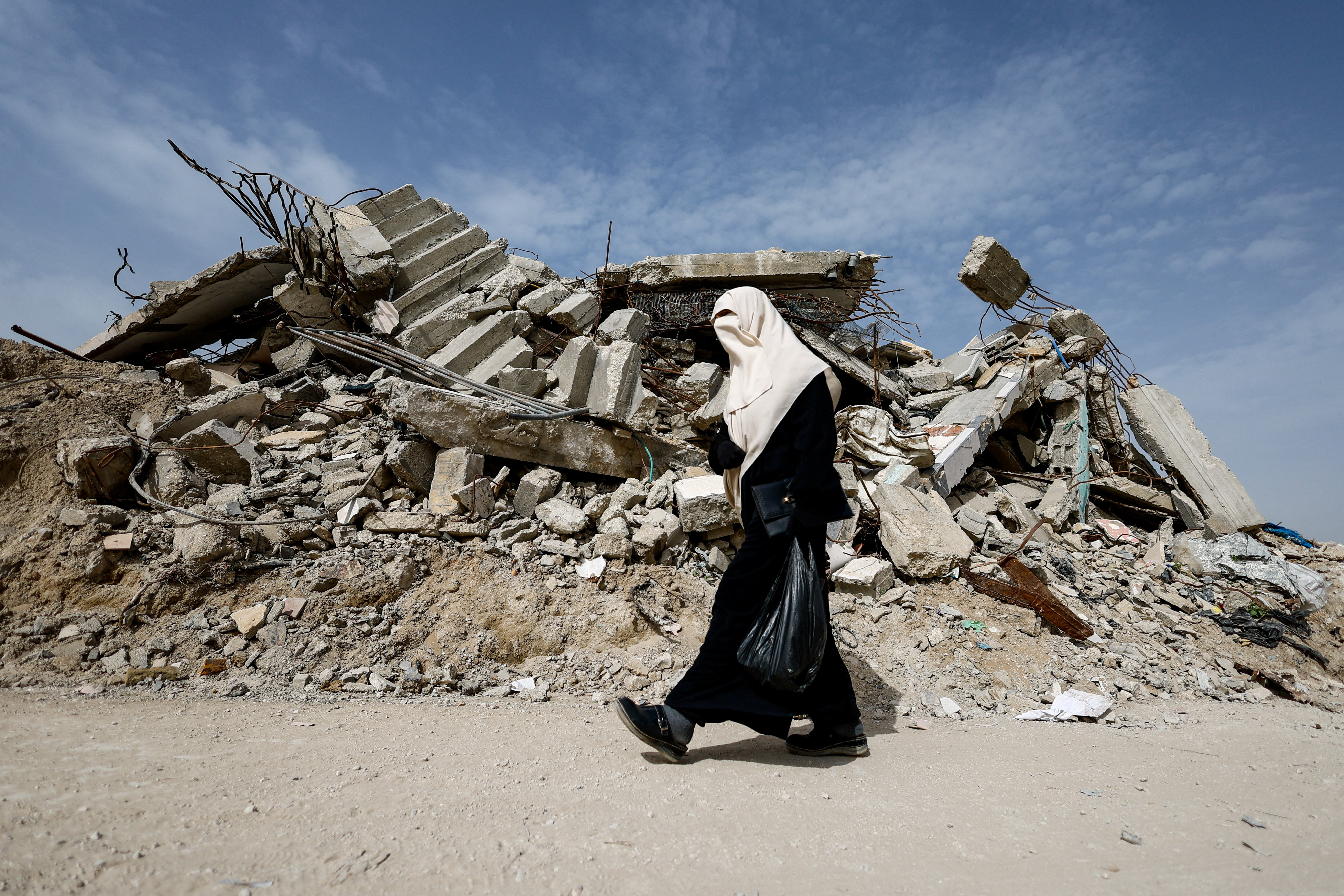 A Palestinian woman walks past the rubble of a residential building destroyed during the war, in Gaza City, January 28, 2026. REUTERS/Mahmoud Issa