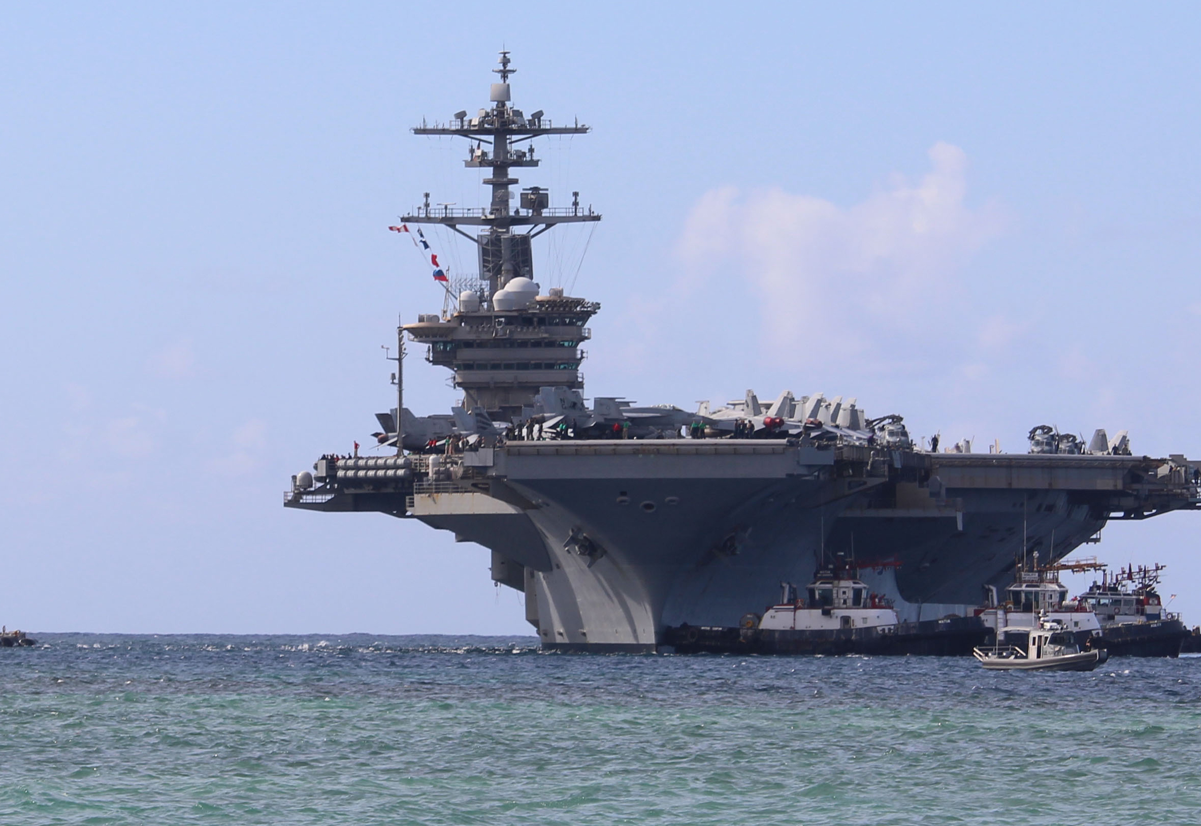 Harbor tug boats guide Nimitz-class aircraft carrier USS Abraham Lincoln as the ship pulls into Naval Base Guam for a scheduled port visit, December 11, 2025. [Valerie Maigue/US Navy]