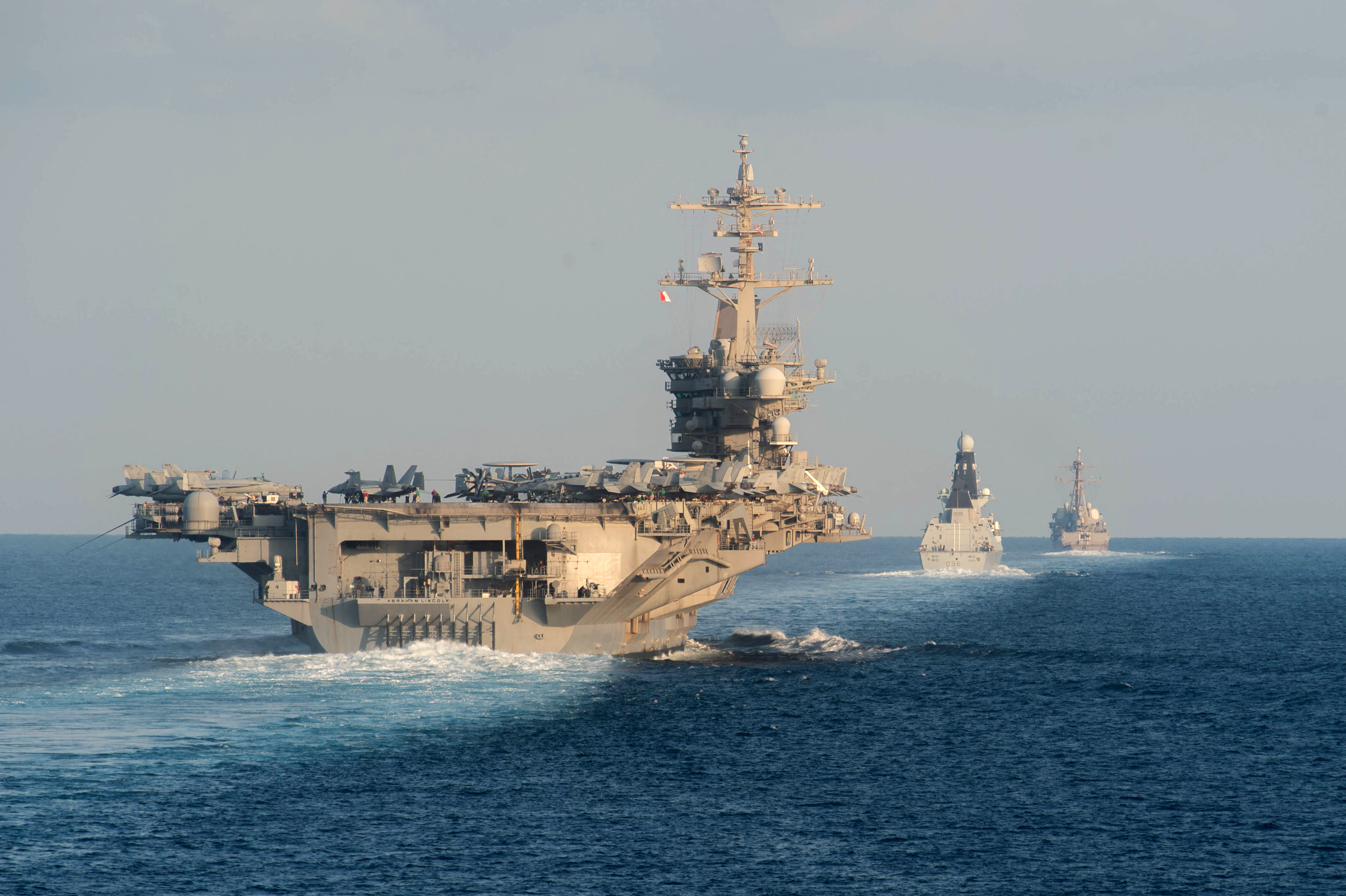(FILES) (L-R) The aircraft carrier USS Abraham Lincoln (L), the air-defense destroyer HMS Defender and the guided-missile destroyer USS Farragut transit the Strait of Hormuz on November 19, 2019. The US will bolster its military presence in the Middle East, deploying additional warships and fighter jets to protect US personnel and defend Israel amid soaring tensions in the region, the Pentagon said on August 2, 2024. The aircraft carrier strike group led by the USS Abraham Lincoln will replace one helmed by the USS Theodore Roosevelt in the region, deputy Pentagon Press Secretary Sabrina Singh said. (Photo by Zachary PEARSON / US NAVY / AFP) / RESTRICTED TO EDITORIAL USE - MANDATORY CREDIT "AFP PHOTO / US NAVY/MASS COMMUNICATION SPECIALIST 3RD CLASS ZACHARY PEARSON" - NO MARKETING NO ADVERTISING CAMPAIGNS - DISTRIBUTED AS A SERVICE TO CLIENTS