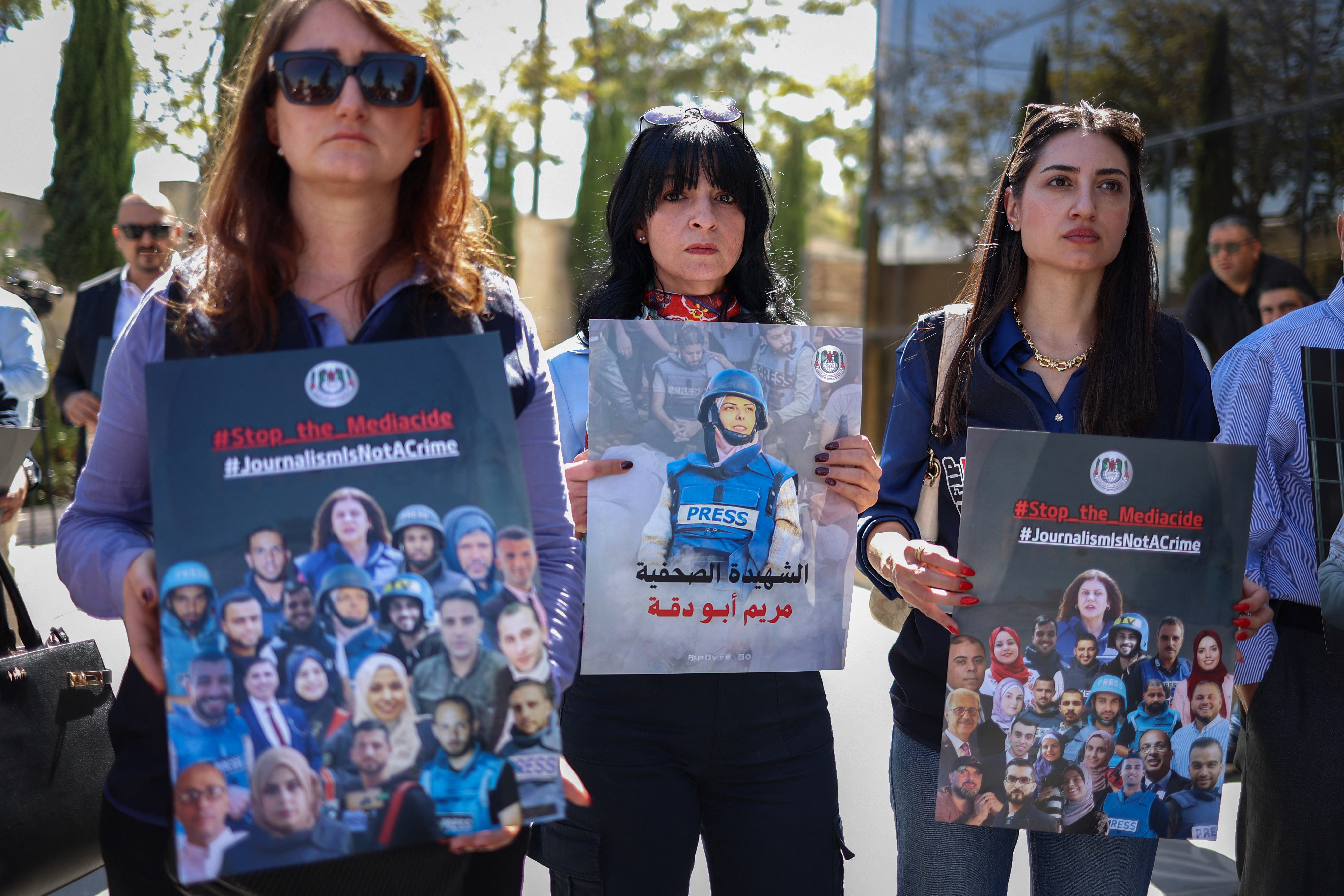 Palestinian journalists and local officials protest, holding up pictures of slain media workers.