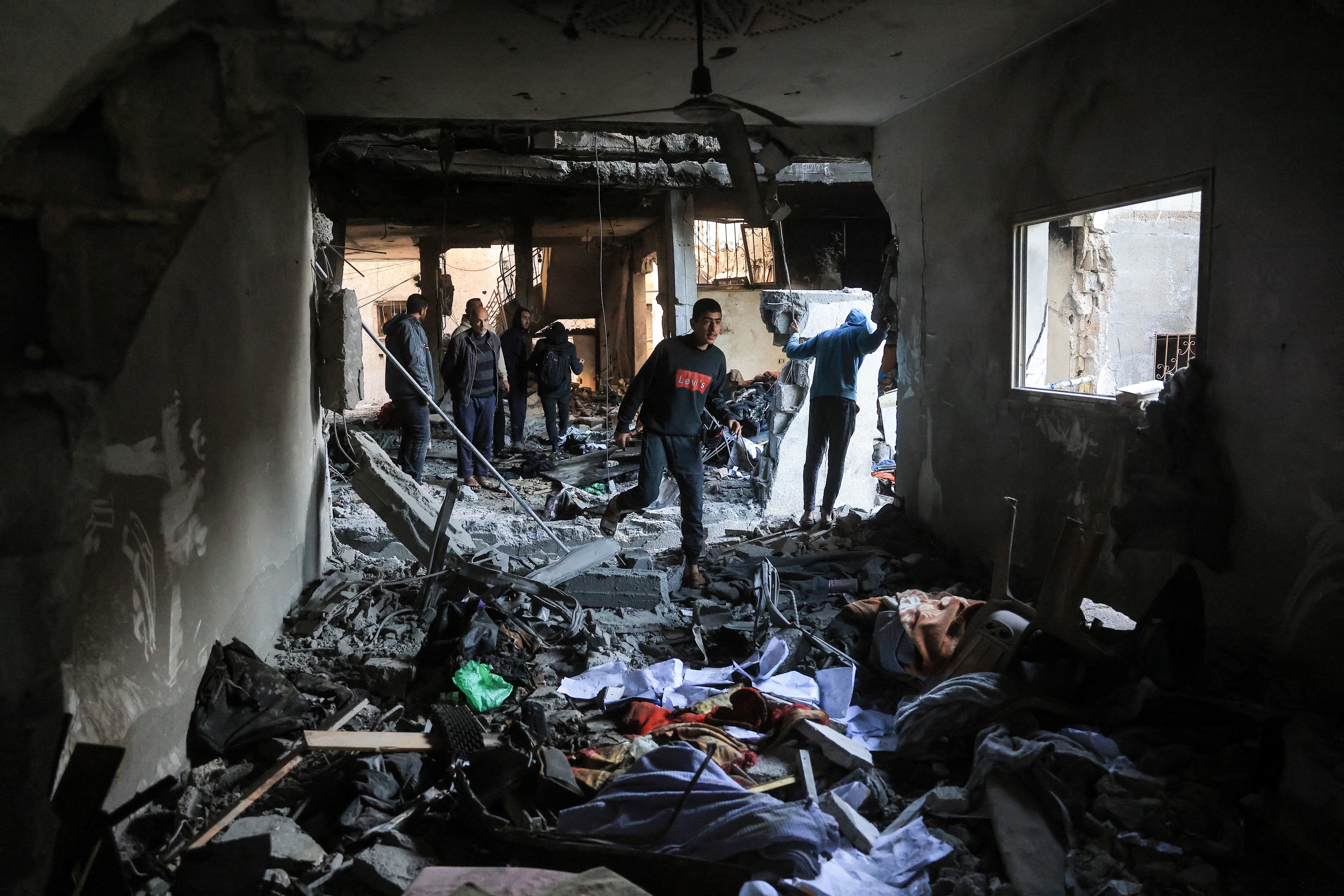 Palestinians survey the destruction of a house after an Israeli military attack on the home of the al-Houli family