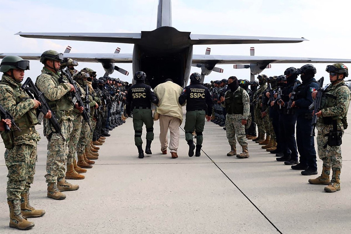 Security forces escorting a man to an airplane.