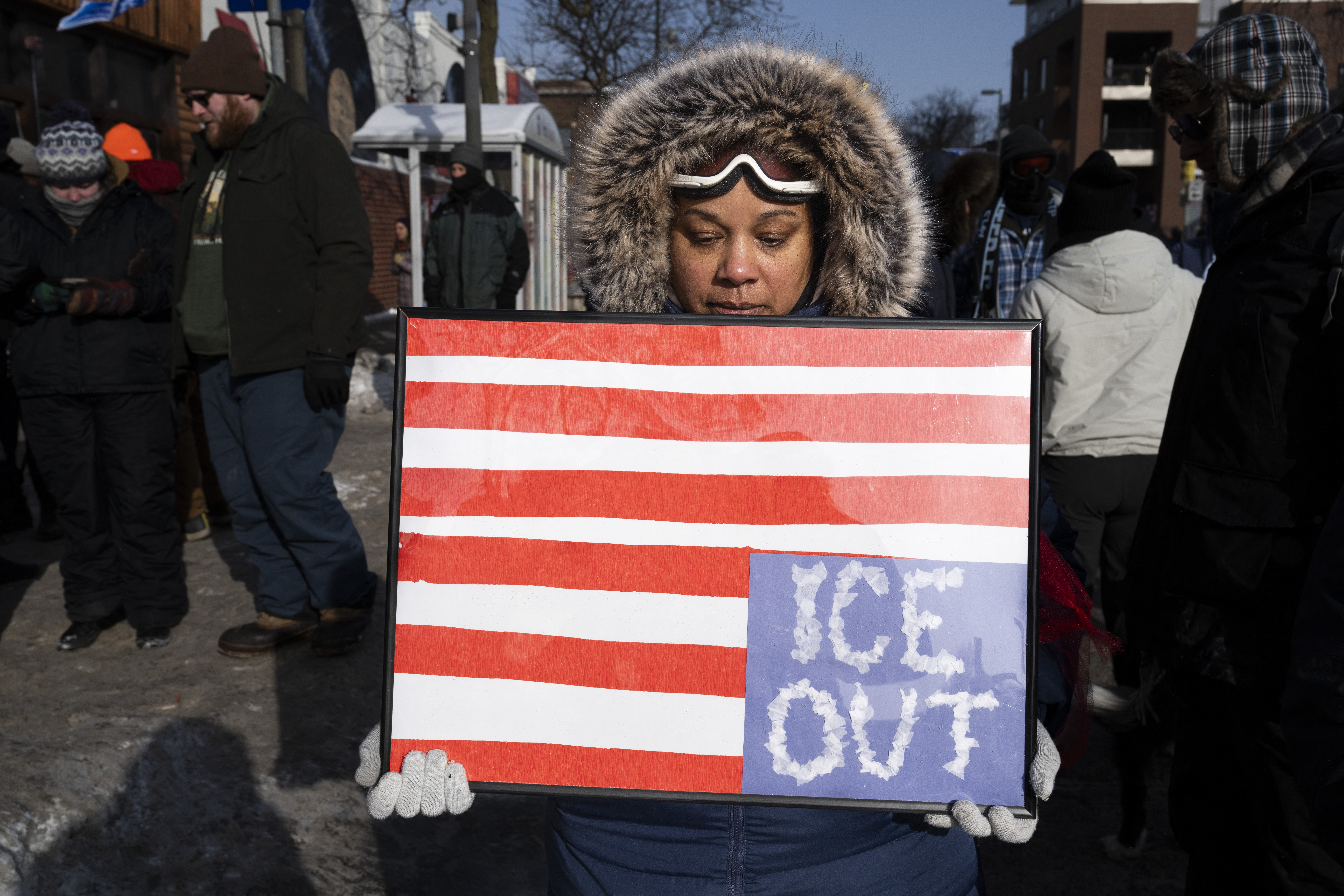 A woman holds a placard with an upside down American flag as mourners gather at a makeshift memorial in the area where Alex Pretti was shot dead a day earlier by federal immigration agents in Minneapolis, Minnesota, on January 25, 2026. On January 24, federal agents shot dead US citizen Alex Pretti, a 37-year-old ICU nurse, while scuffling with him on an icy roadway, less than three weeks after an immigration officer shot and killed Renee Good, also 37, in her car. [Photo by ROBERTO SCHMIDT / AFP]