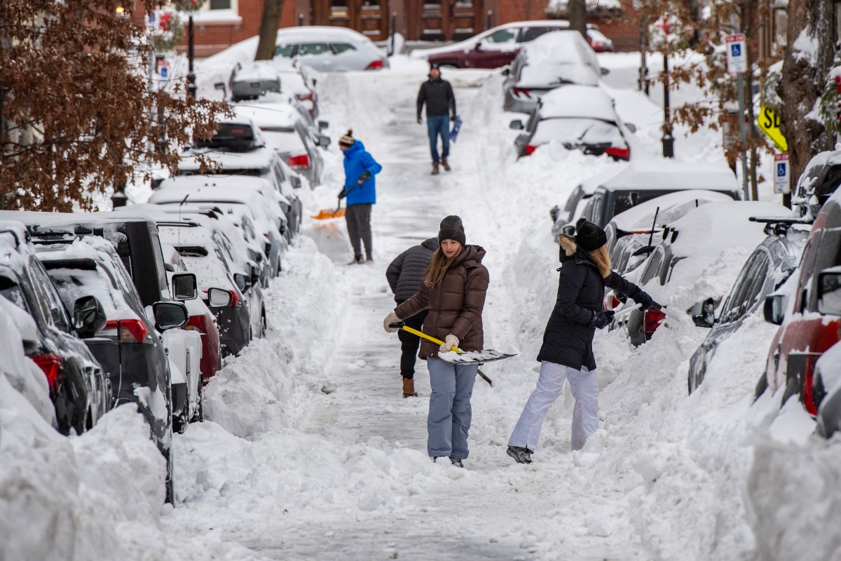 People shovel snow along a residential street in the Charlestown neighborhood in Boston, Massachusetts on January 26, 2026. A monster storm barreling across the United States had killed at least 11 people on Monday, prompting warnings to stay off the roads, mass flight cancelations and power outages after a weekend of misery. The storm dumped snow, sleet and freezing rain across swathes of the country from Texas to New England, with temperatures set to fall dangerously low this week.