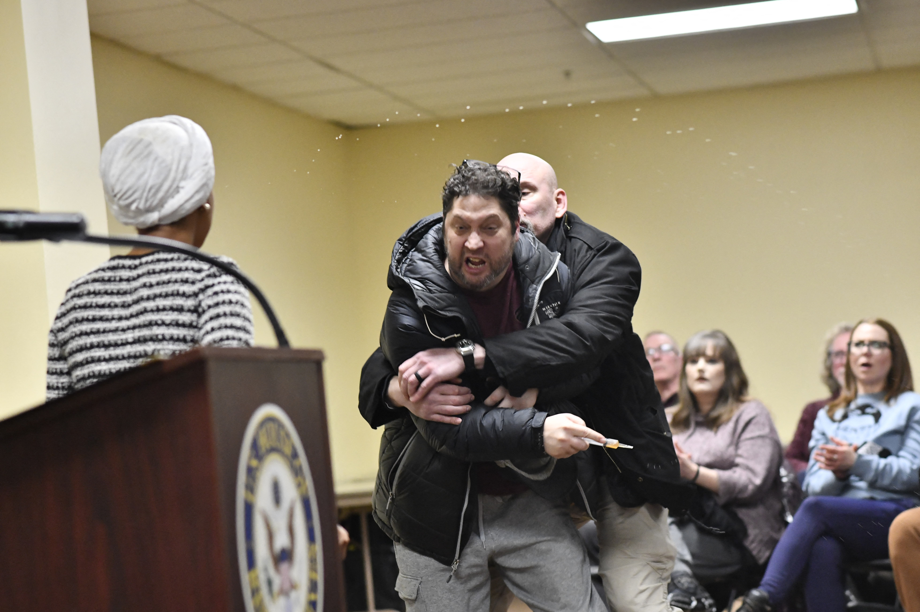 A man is tackled after spraying an unknown substance at US Representative Ilhan Omar (D-MN) (L) during a town hall she was hosting in Minneapolis, Minnesota, on January 27, 2026. (Photo by Octavio JONES / AFP)