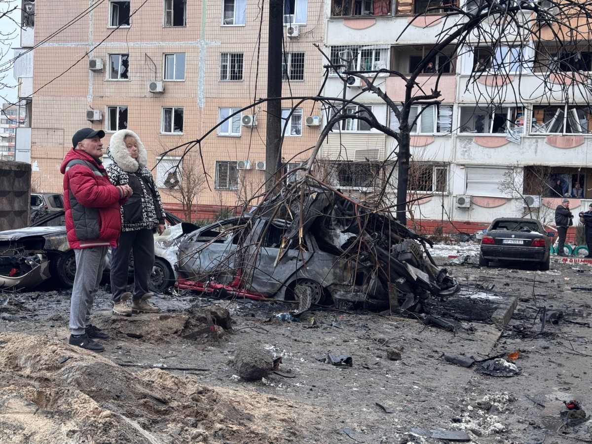 People stand next to burned cars in an area hit by an air attack in a residential neighbourhood in Zaporizhia