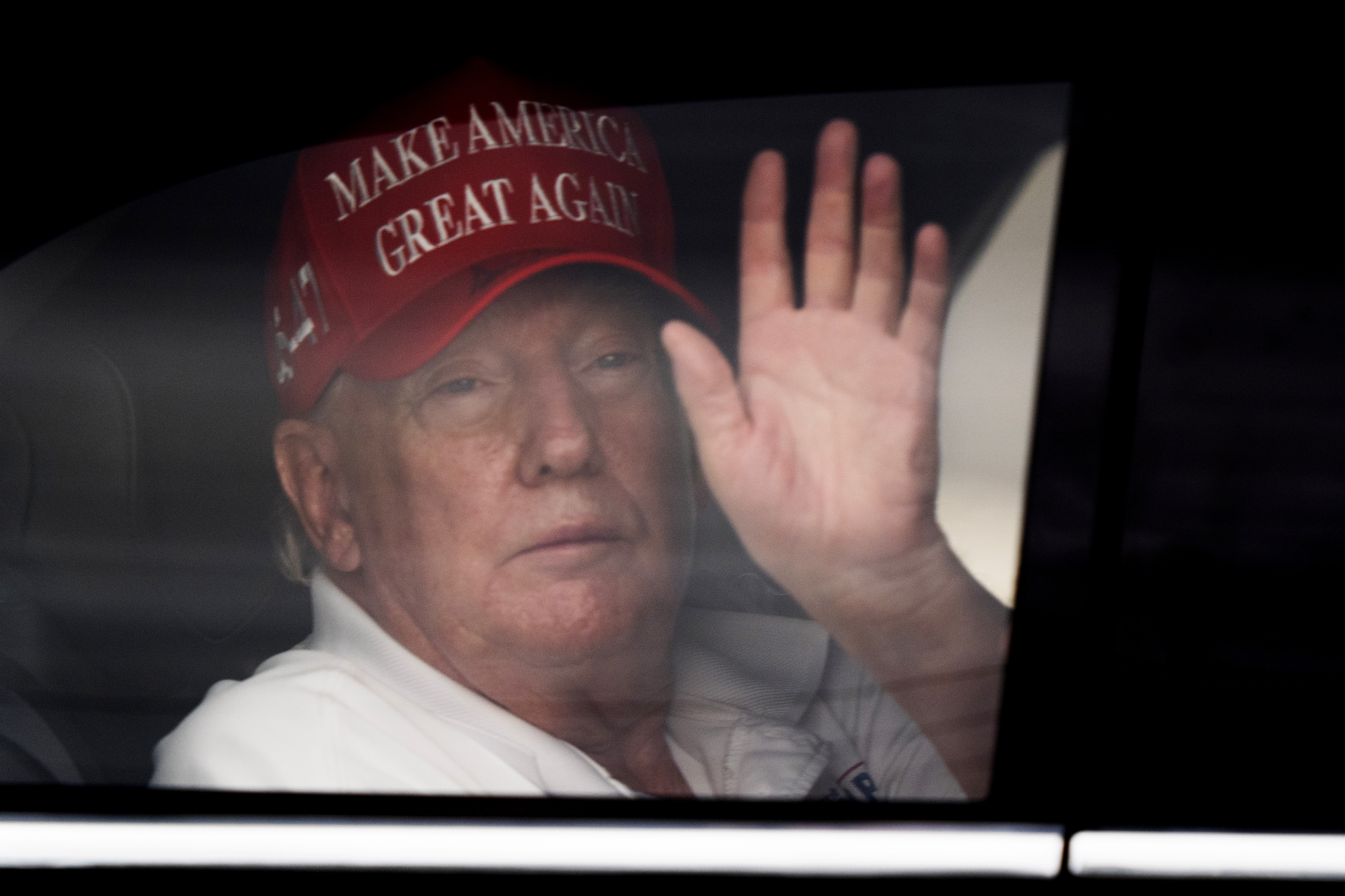 Trump waves from a limo at his golf course