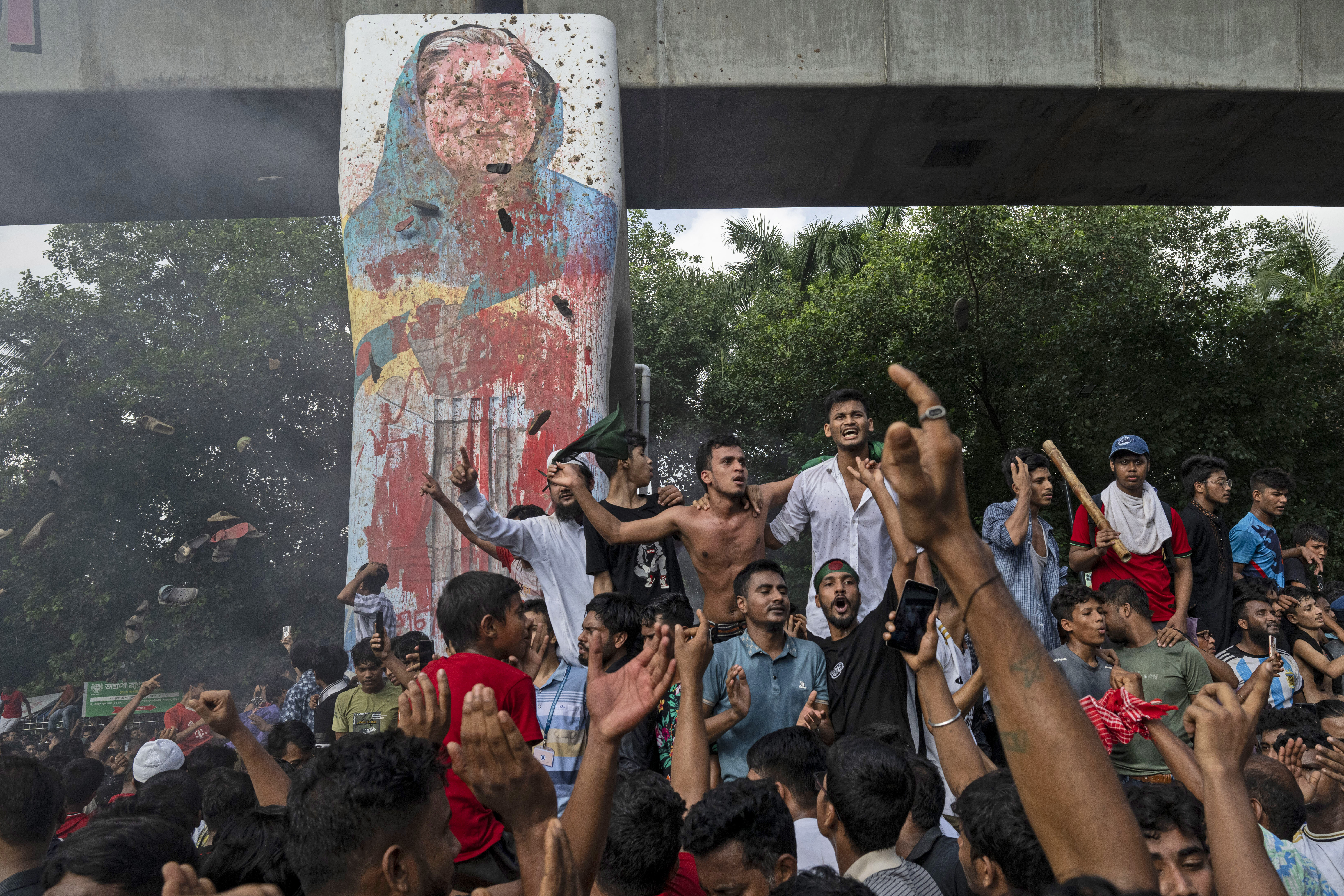 FILE - Protesters celebrate beside a defaced portrait of Prime Minister Sheikh Hasina after news of her resignation, in Dhaka, Bangladesh, on Aug. 5, 2024. (AP Photo/Fatima Tuj Johora File)