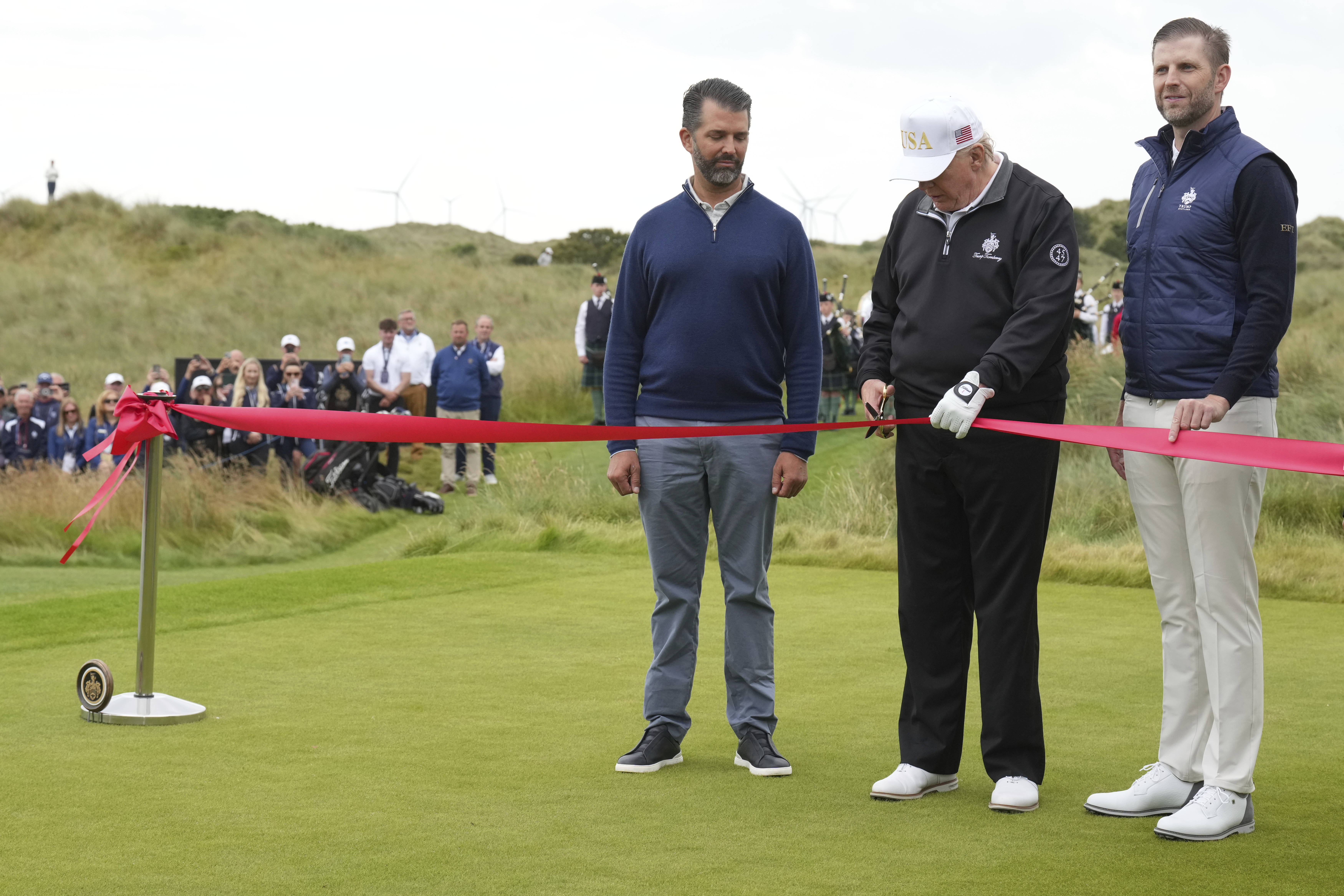 Trump cuts a red ribbon with his son Don Jr in Scotland