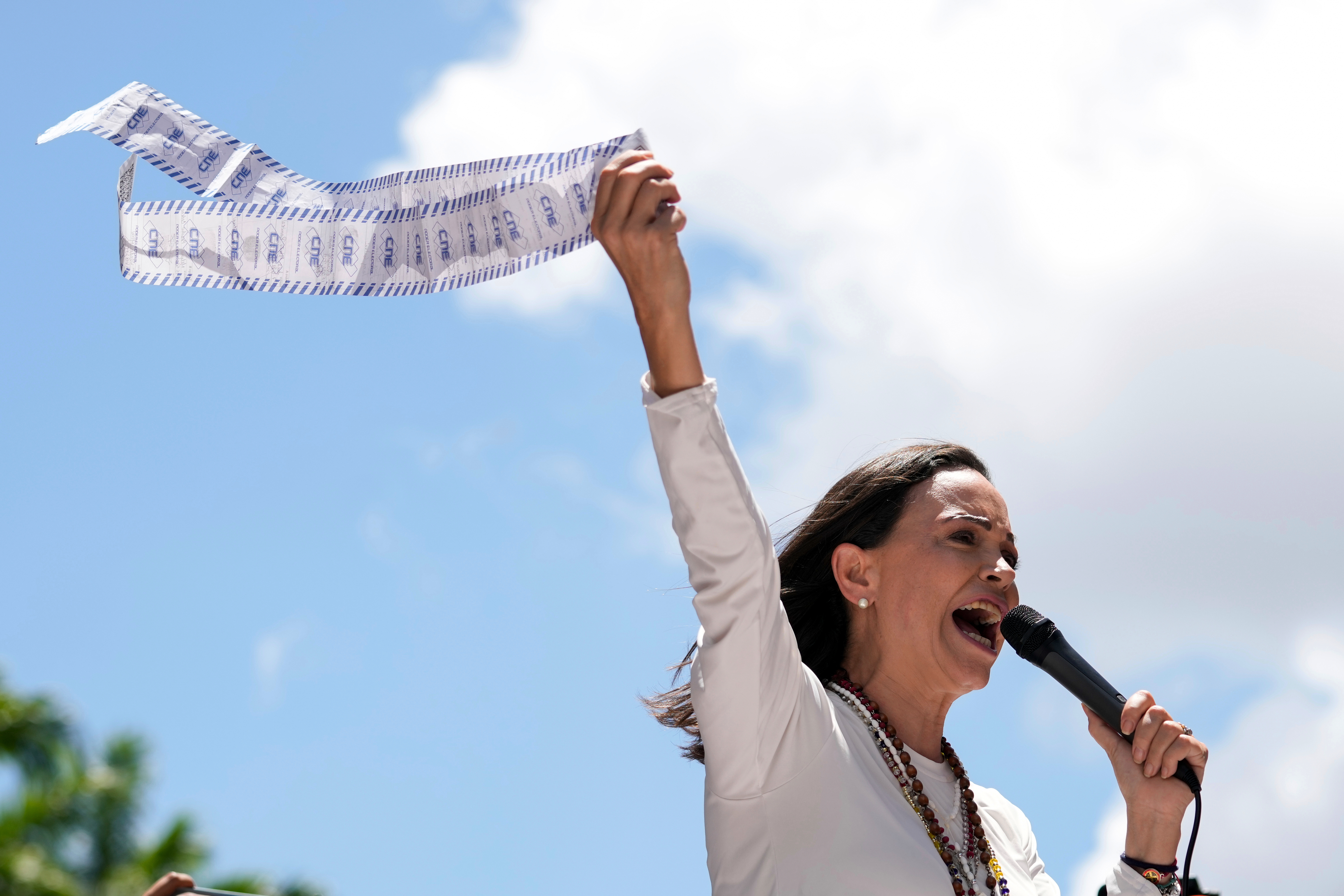 Maria Corina Machado holds up a tally sheet as she speaks into a microphone