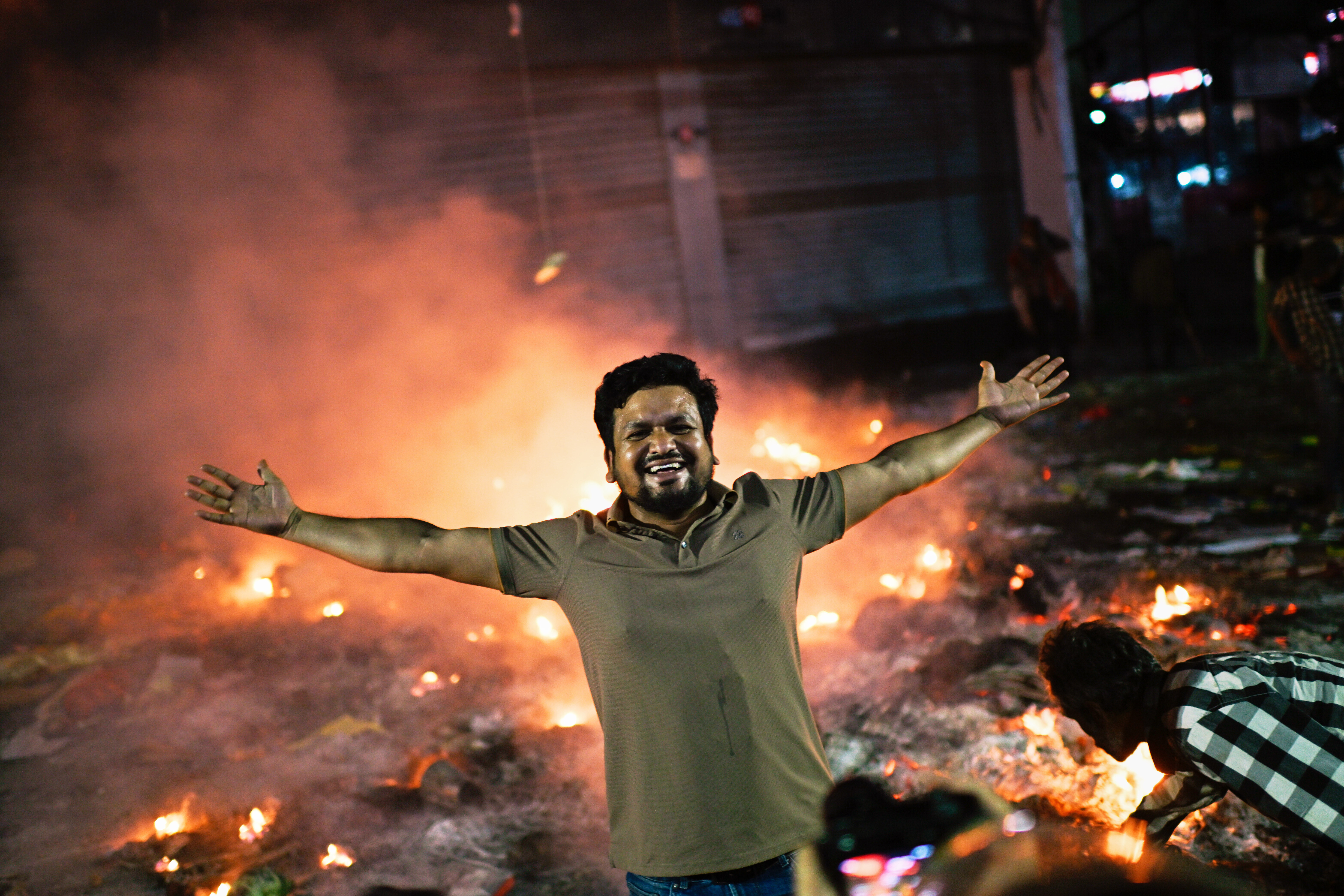 A protester reacts to the camera near the premises of the Prothom Alo daily newspaper which was set on fire by angry protesters after news reached the country from Singapore of the death of a prominent activist Sharif Osman Hadi, in Dhaka, Bangladesh, Friday, Dec. 19, 2025. (AP Photo/Mahmud Hossain Opu)