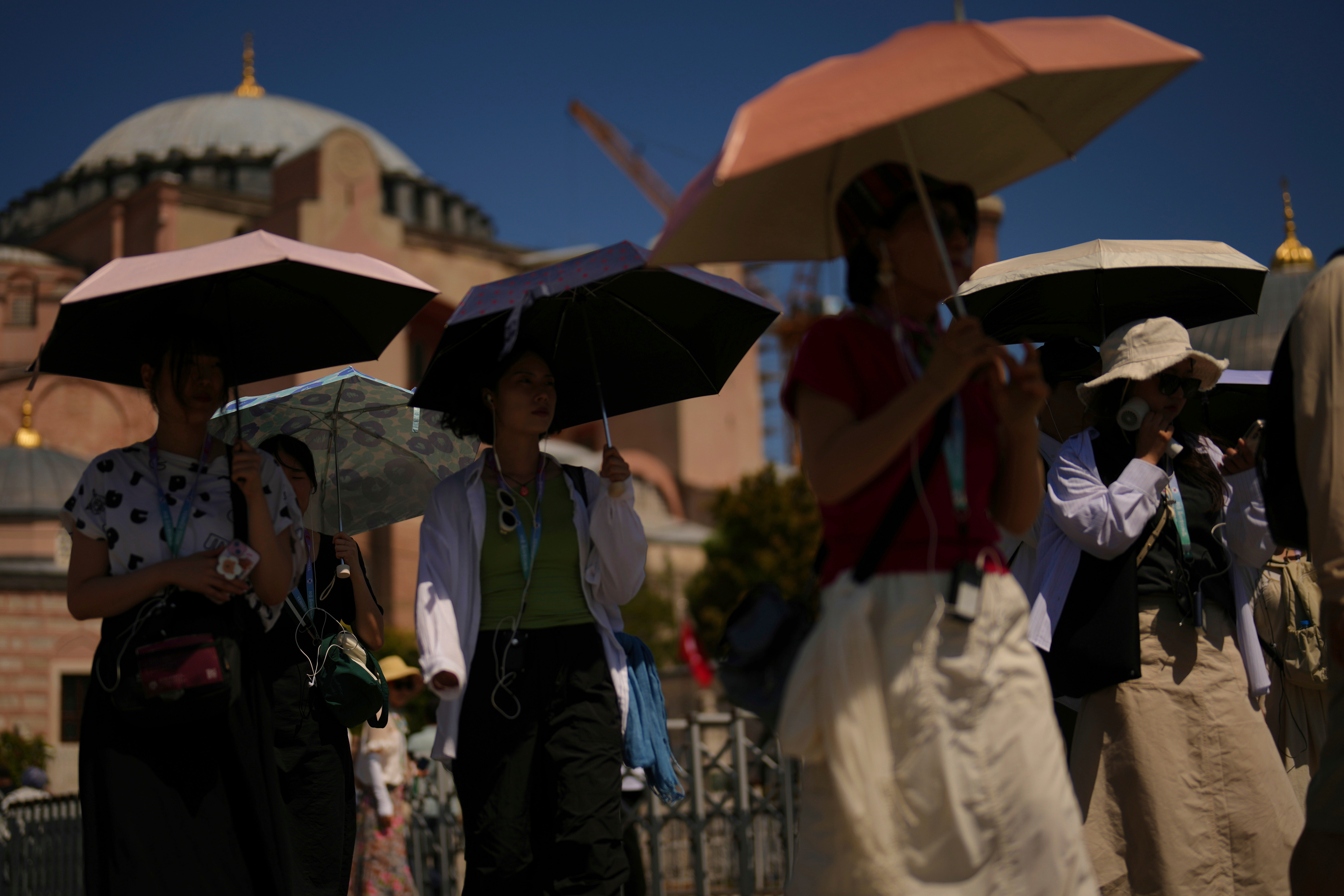 Tourists use umbrellas to shelter against the sun outside Hagia Sophia mosque in Istanbul.