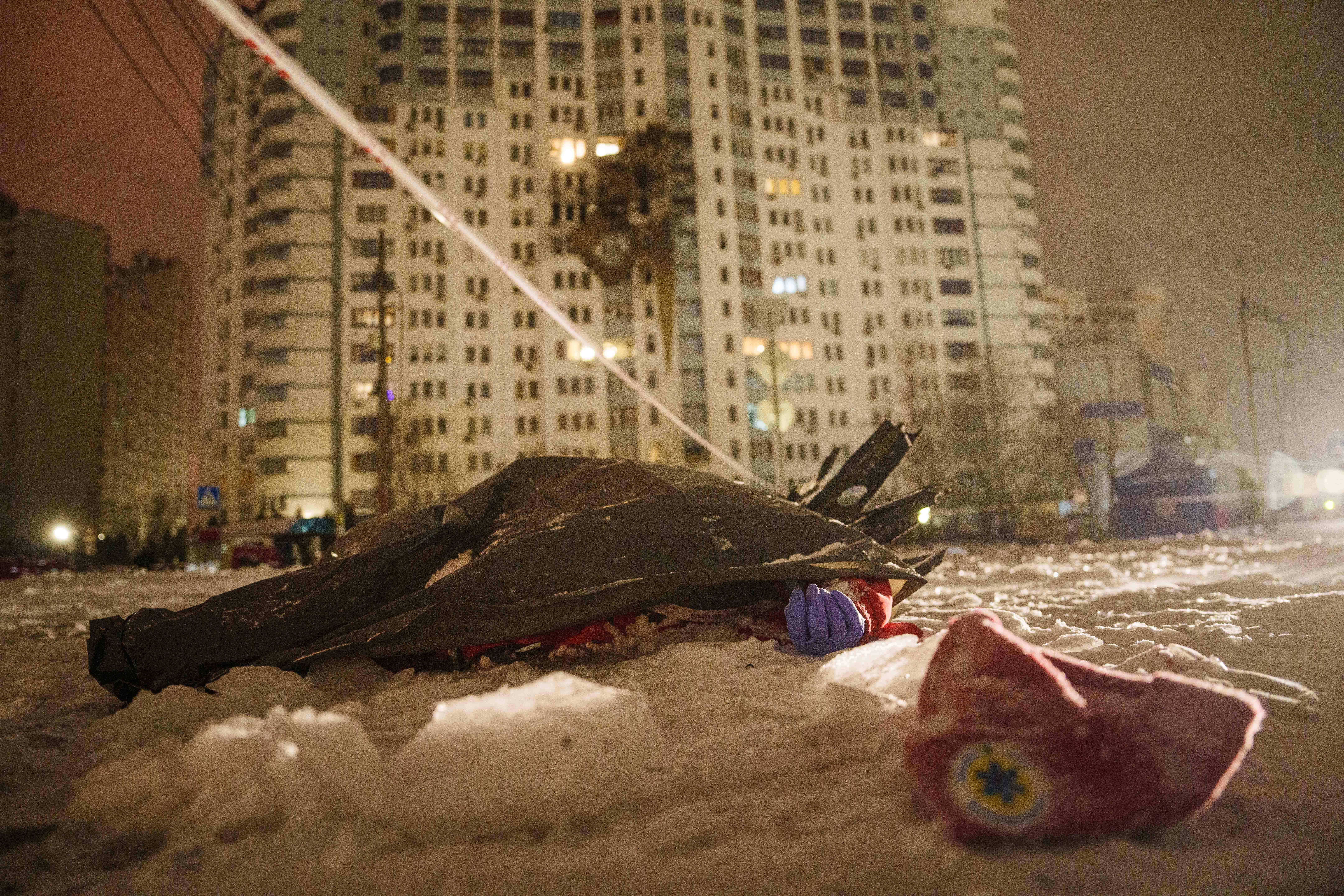 The dead body of a paramedic lies on the ground in front of a residential building damaged by a Russian strike on Kyiv, Ukraine, Friday, Jan. 9, 2026. (AP Photo/Evgeniy Maloletka)