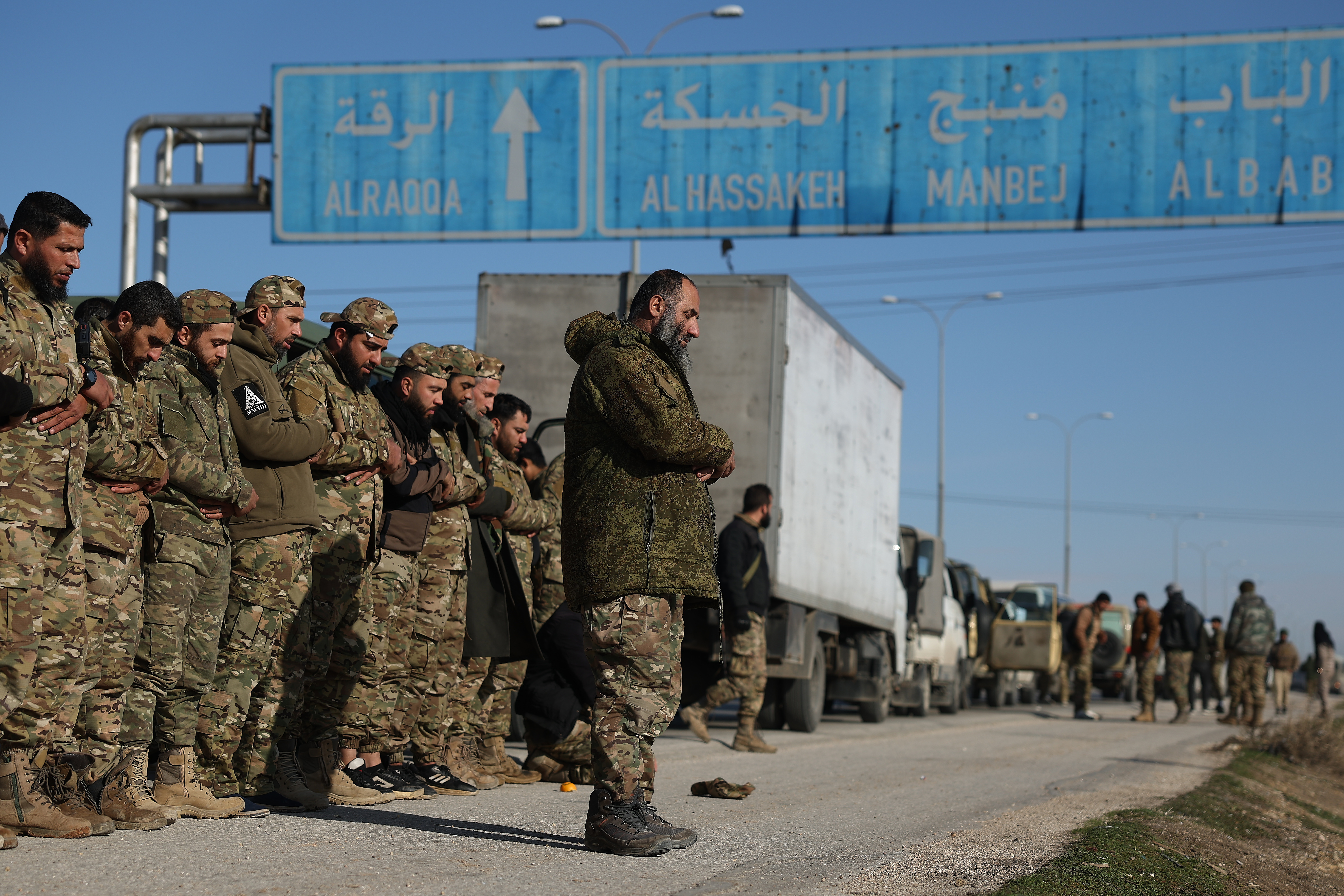 Syrian government soldiers pray on a highway as they head to Deir Hafer village amid the possibility of escalating fighting with the Kurdish fighters, in eastern Aleppo, Syria, Wednesday, Jan. 14, 2026. (AP Photo/Ghaith Alsayed)