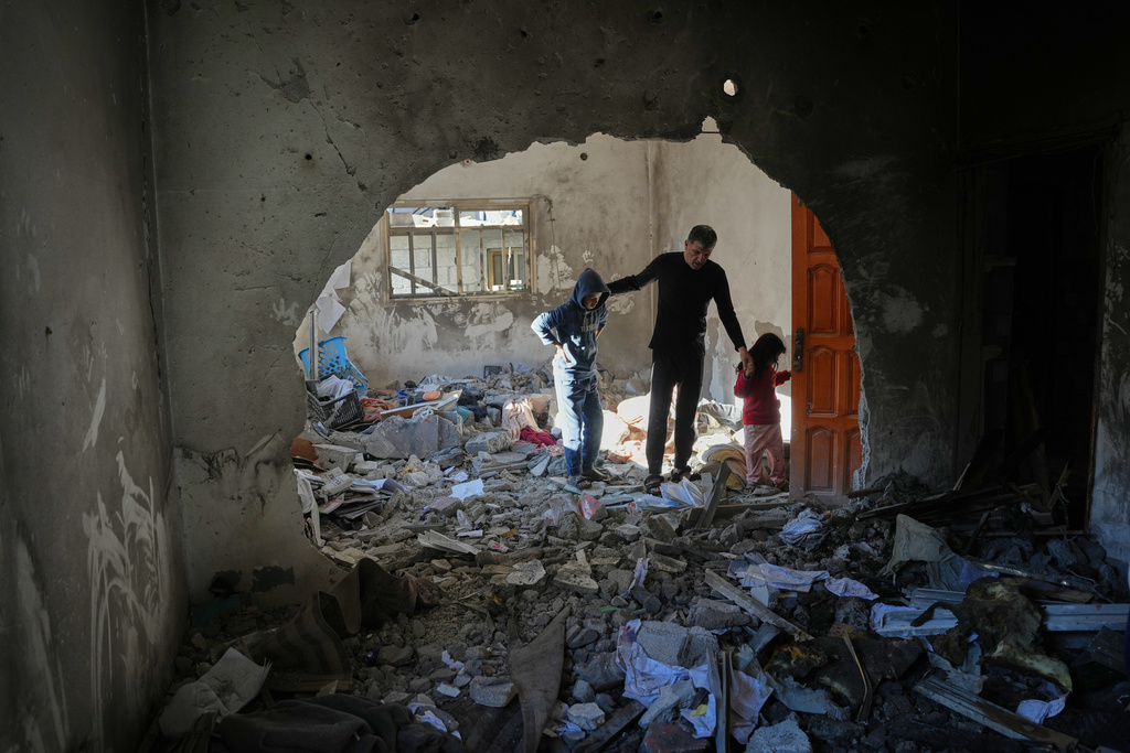 Palestinians inspect the rubble of the al-Hawli family home, destroyed in an Israeli strike in Deir al-Balah, Gaza