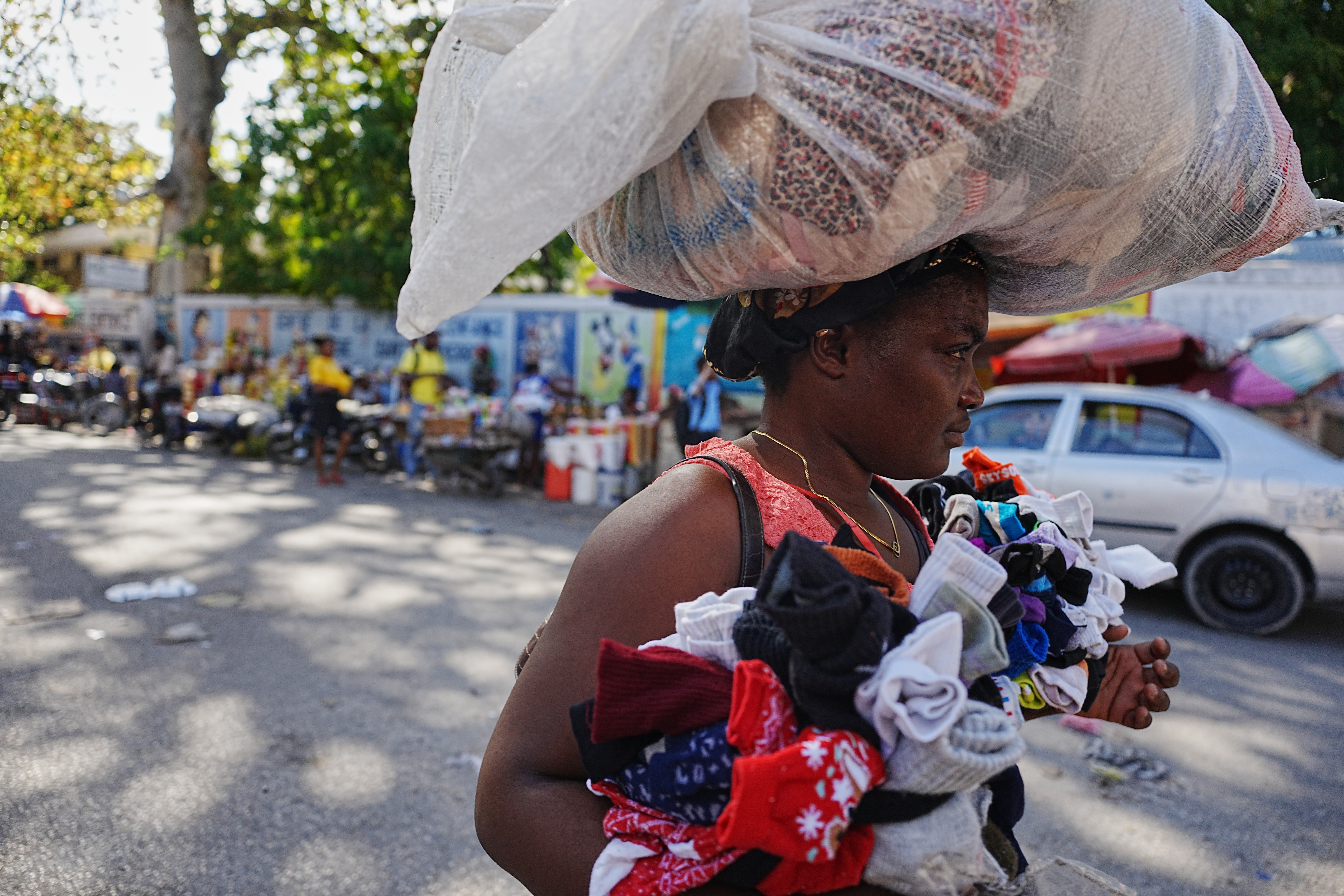 A Haitian woman balances a bag on her head as she sells items in the street