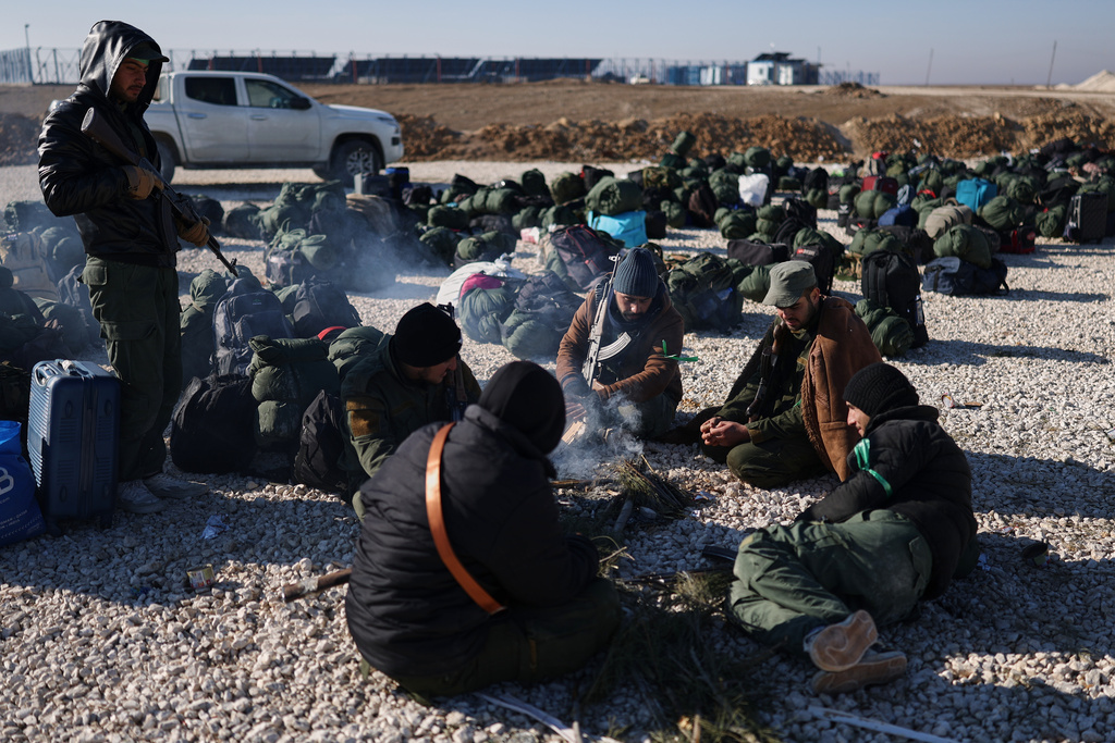Syrian government forces with their luggage wait to enter the al-Hol camp in northeastern Syria