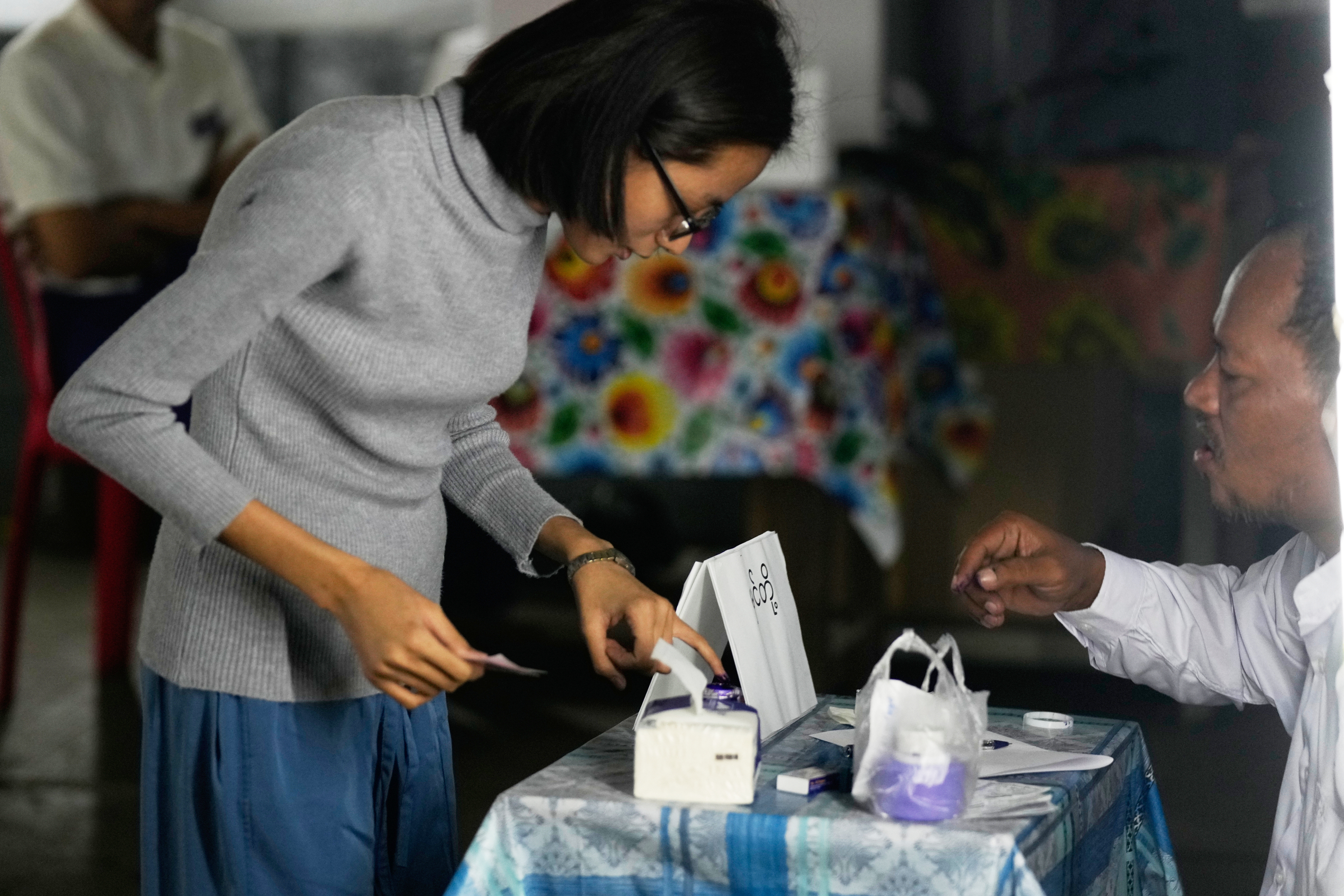 A voter dips her finger in an ink bottle after casting ballot a polling station during the third phase of general election Sunday, Jan.25, 2026, in Yangon, Myanmar. (AP Photo/Thein Zaw)