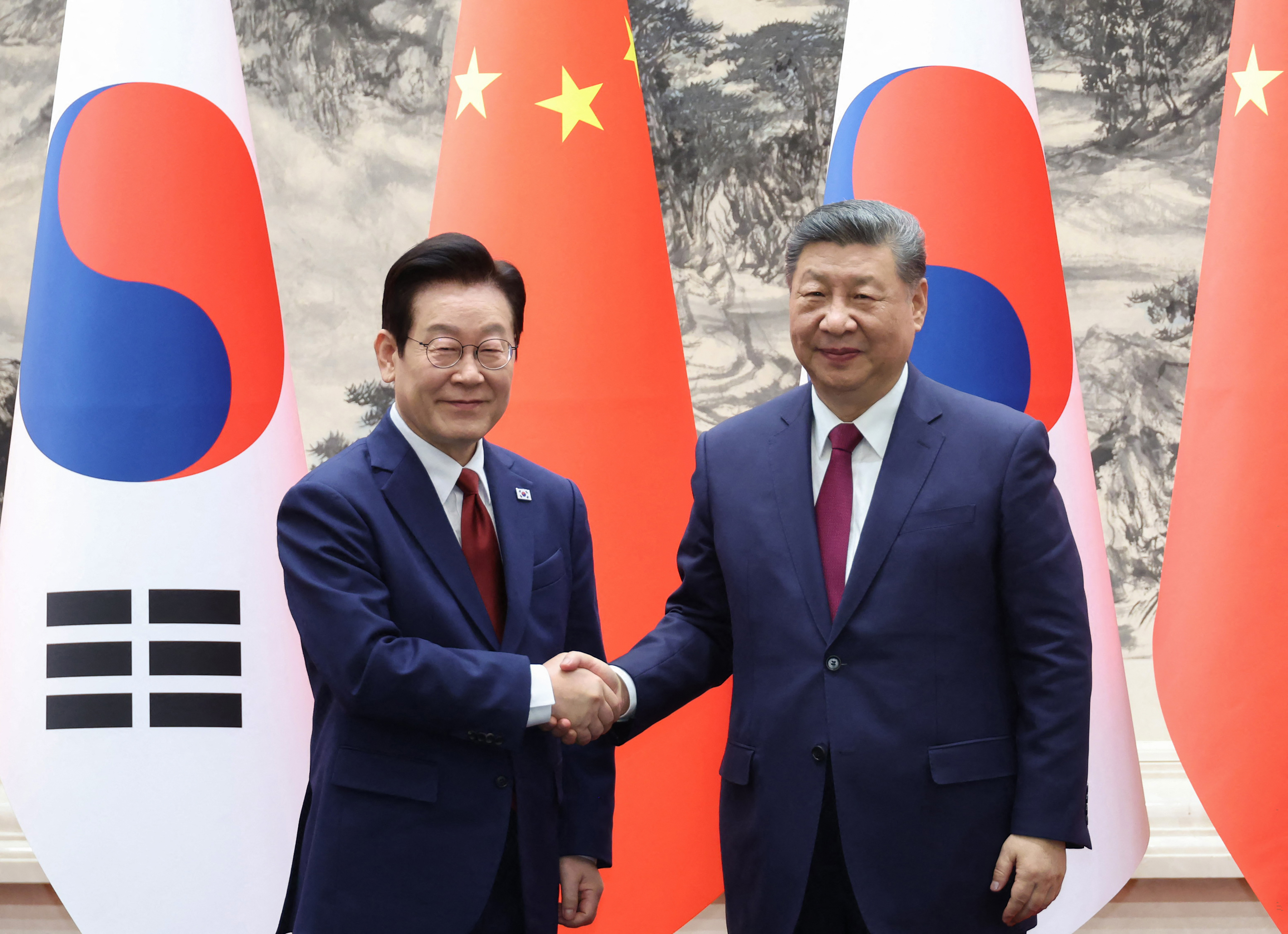 South Korea's President Lee Jae Myung (L) shakes hands with China's President Xi Jinping.