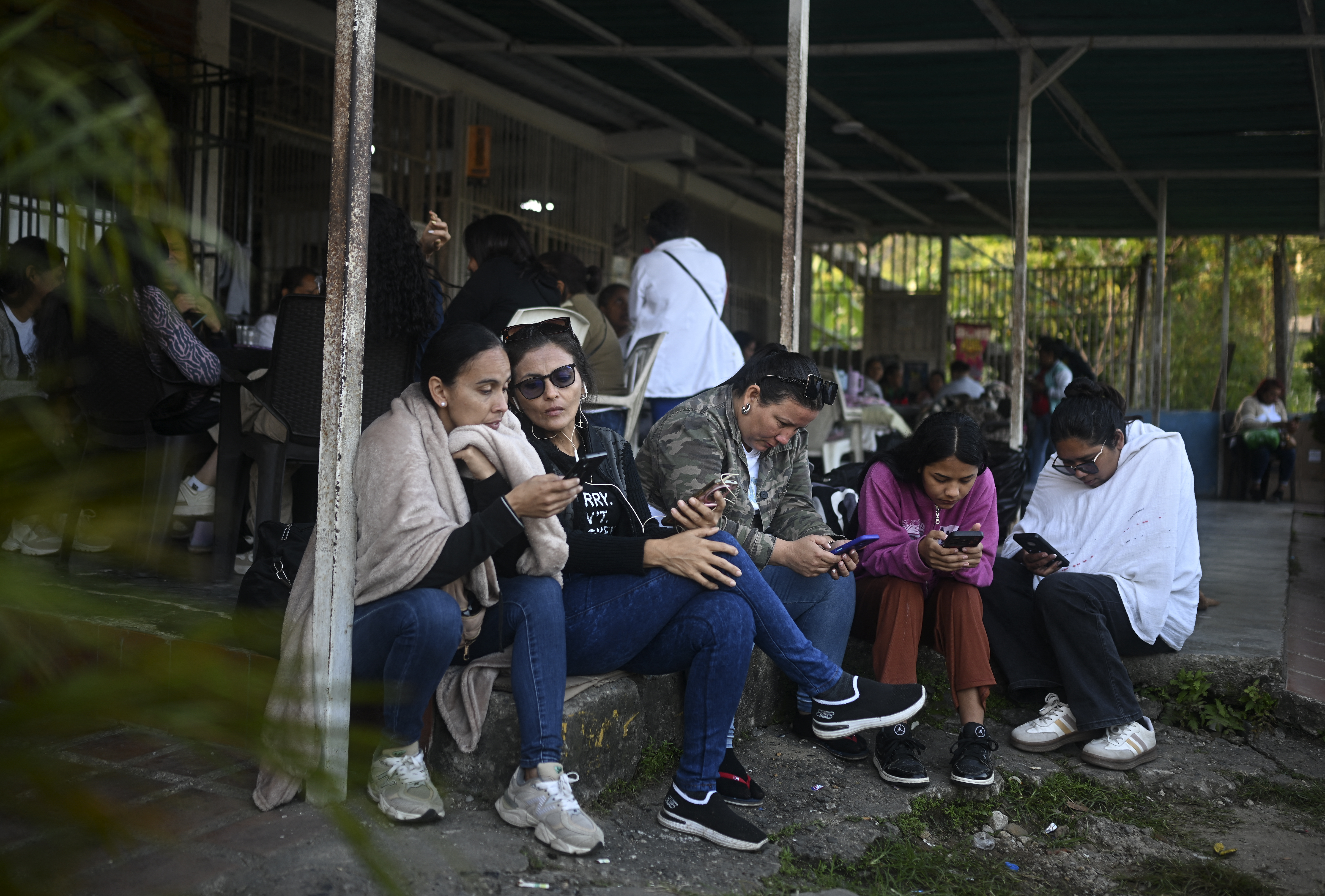 Relatives of inmates check their mobile phones while waiting for news on the release of prisoners, outside El Rodeo I prison in Guatire, Miranda State, some 30 kilometers east of Caracas on January 12, 2026.