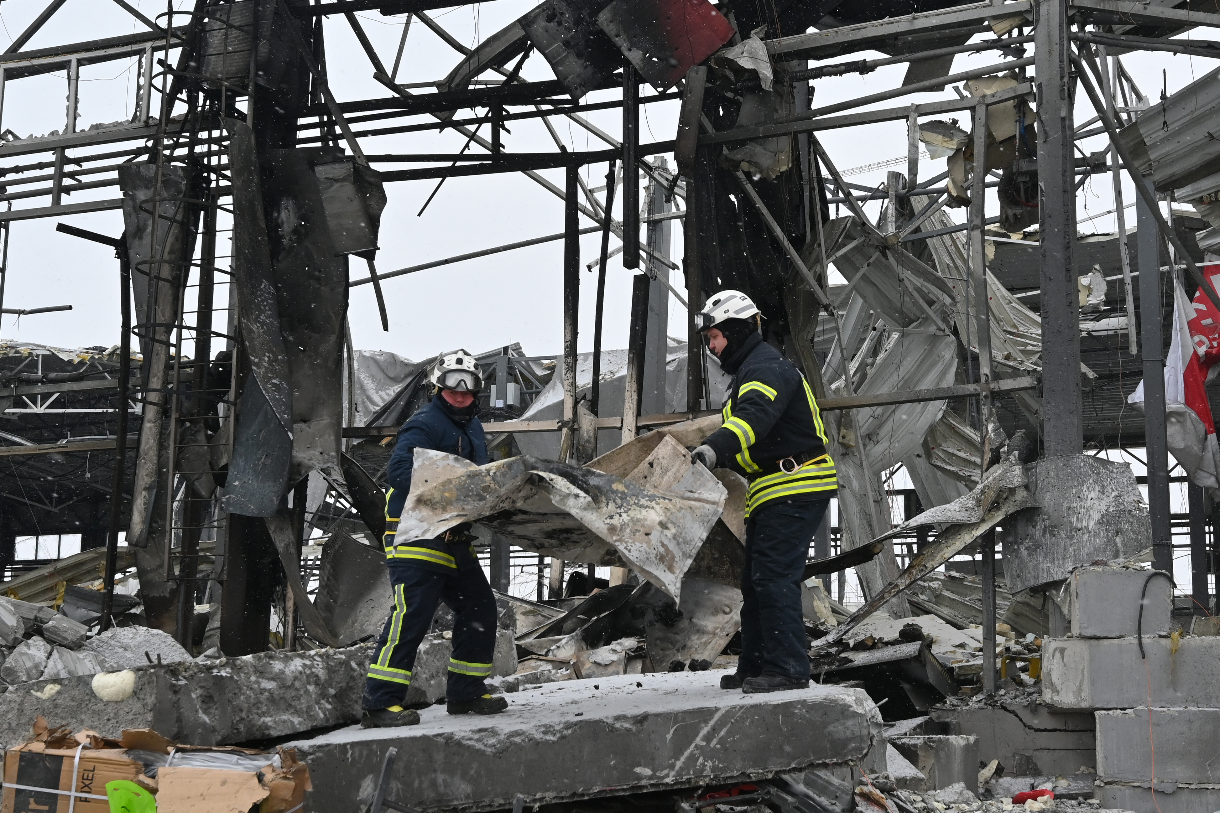 Ukrainian rescuers clear the rubble at the site of a heavily damaged Nova Poshta postal company terminal following an air attack in Novyi Korotych, Kharkiv region on January 13, 2026, amid the Russian invasion of Ukraine.