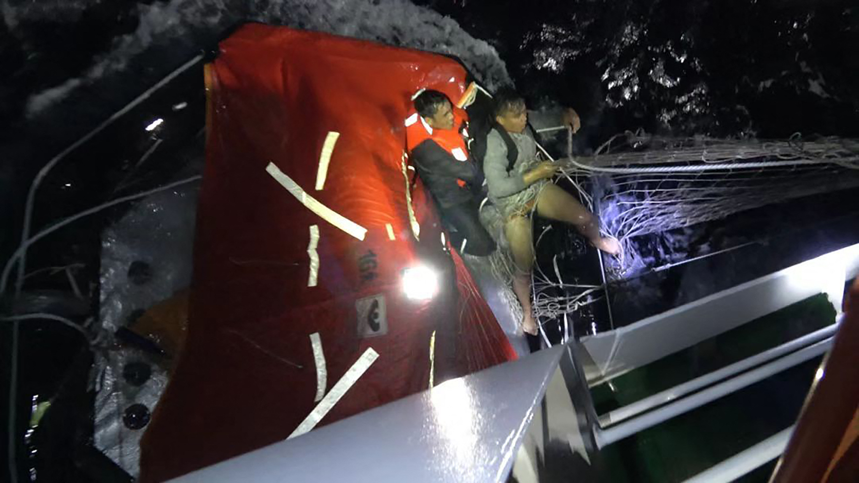This handout from the Chinese Coast Guard taken and released by the Chinese embassy in Manila on January 23, 2026 shows a Chinese Coast Guard personnel rescueing a Filipino crew member of a capsized cargo ship near the contested Scarborough Shoal in the South China Sea.