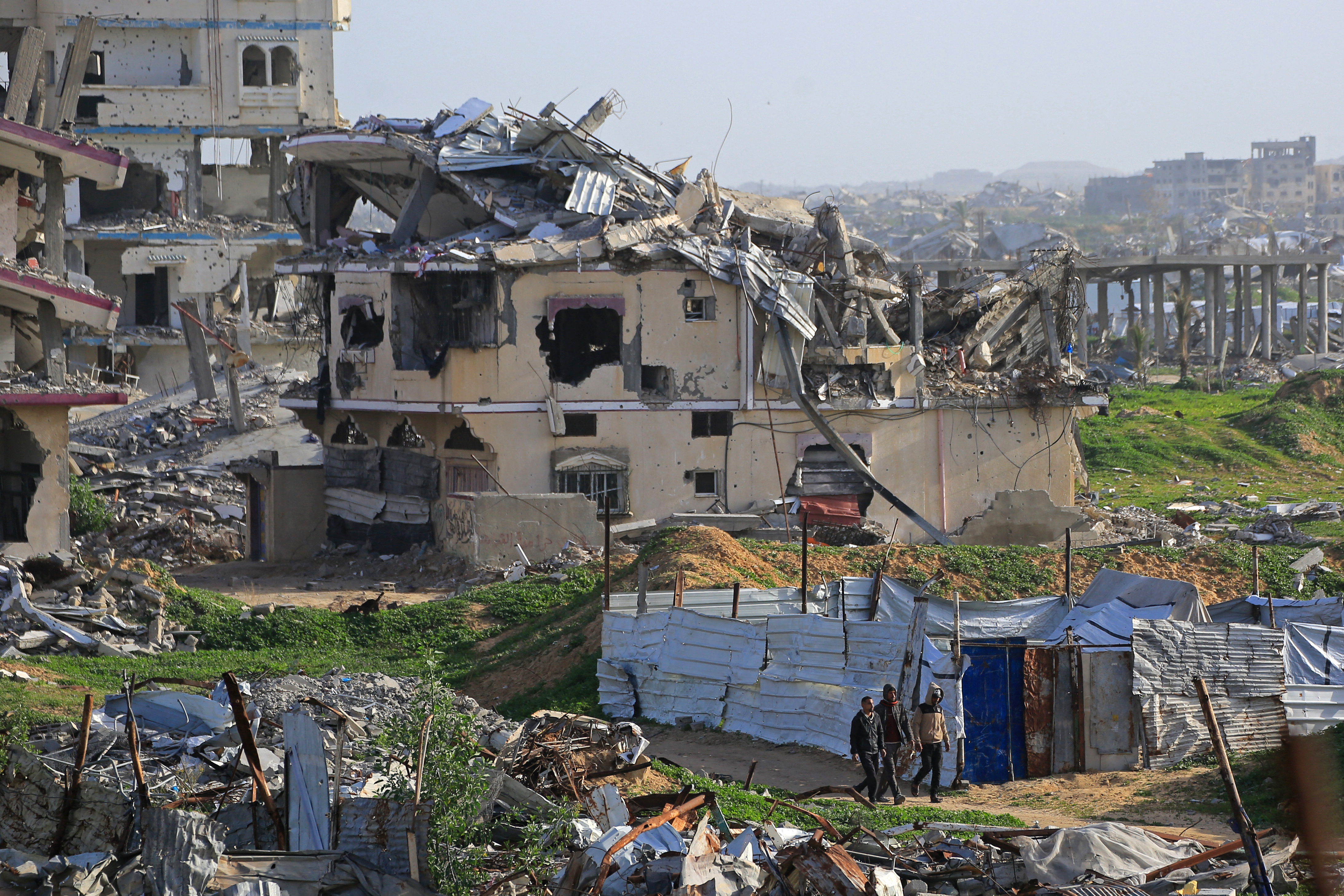 Palestinians walk amid destroyed buildings in Khan Yunis, in the southern Gaza Strip on January 25, 2026.