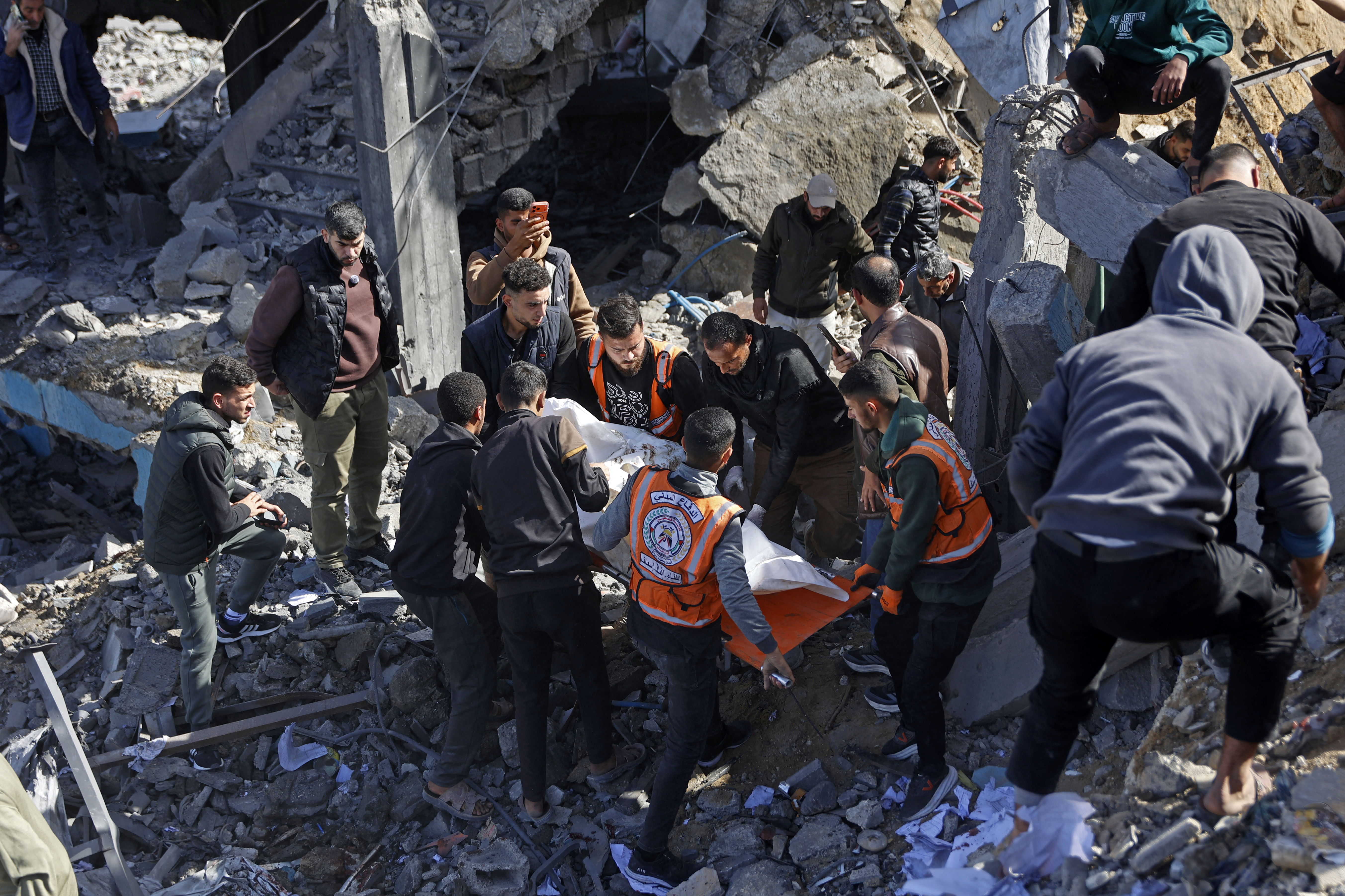Rescuers carry the body of a victim amid the debris of Sheikh Radwan police station in Gaza City on January 31, 2026, following an Israeli air strike.