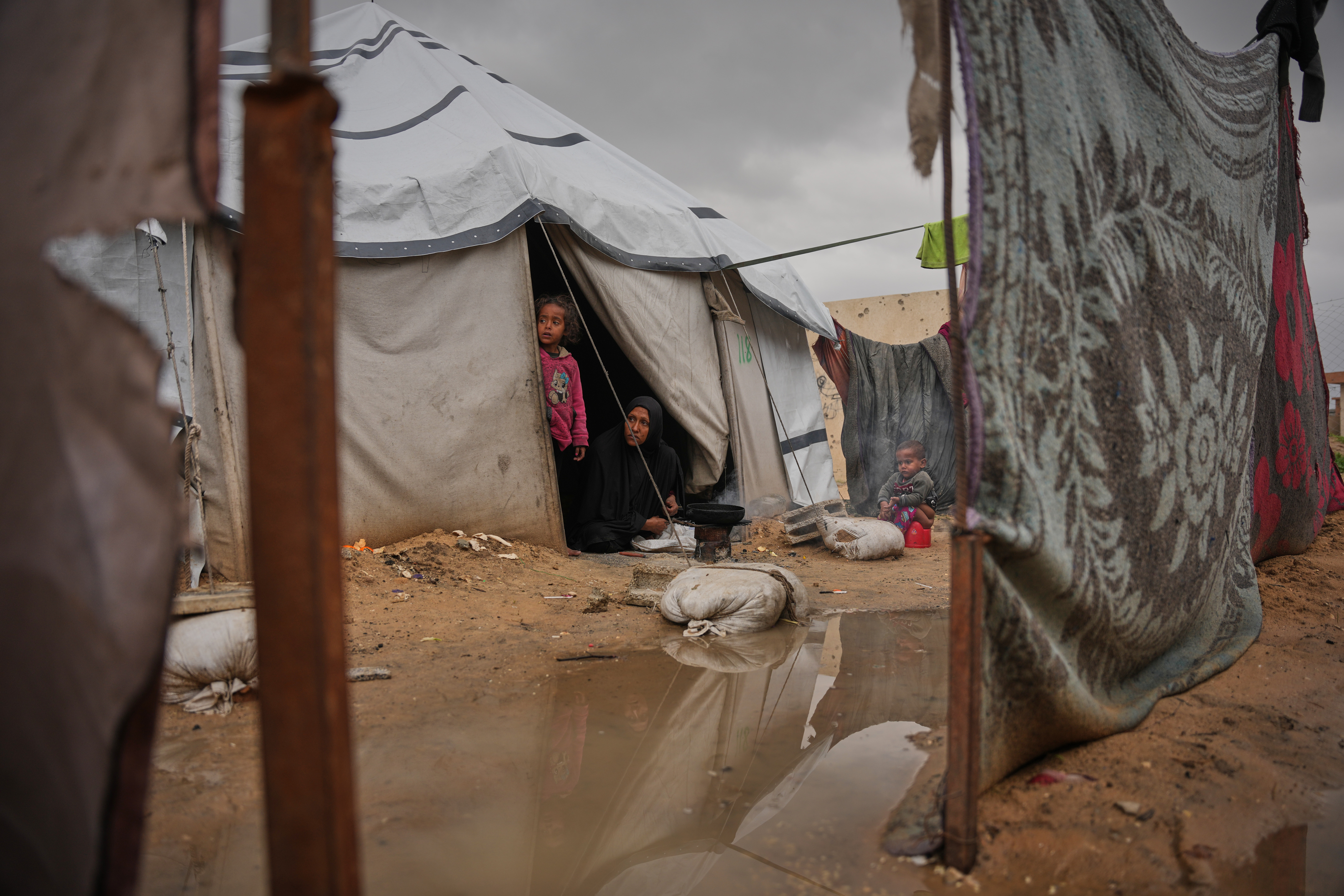 Nanaa Abu Jari cooks outside her tent after it was flooded by rainwater in Nuseirat, central Gaza Strip, Friday, Jan. 2, 2026. (AP Photo/Abdel Kareem Hana)