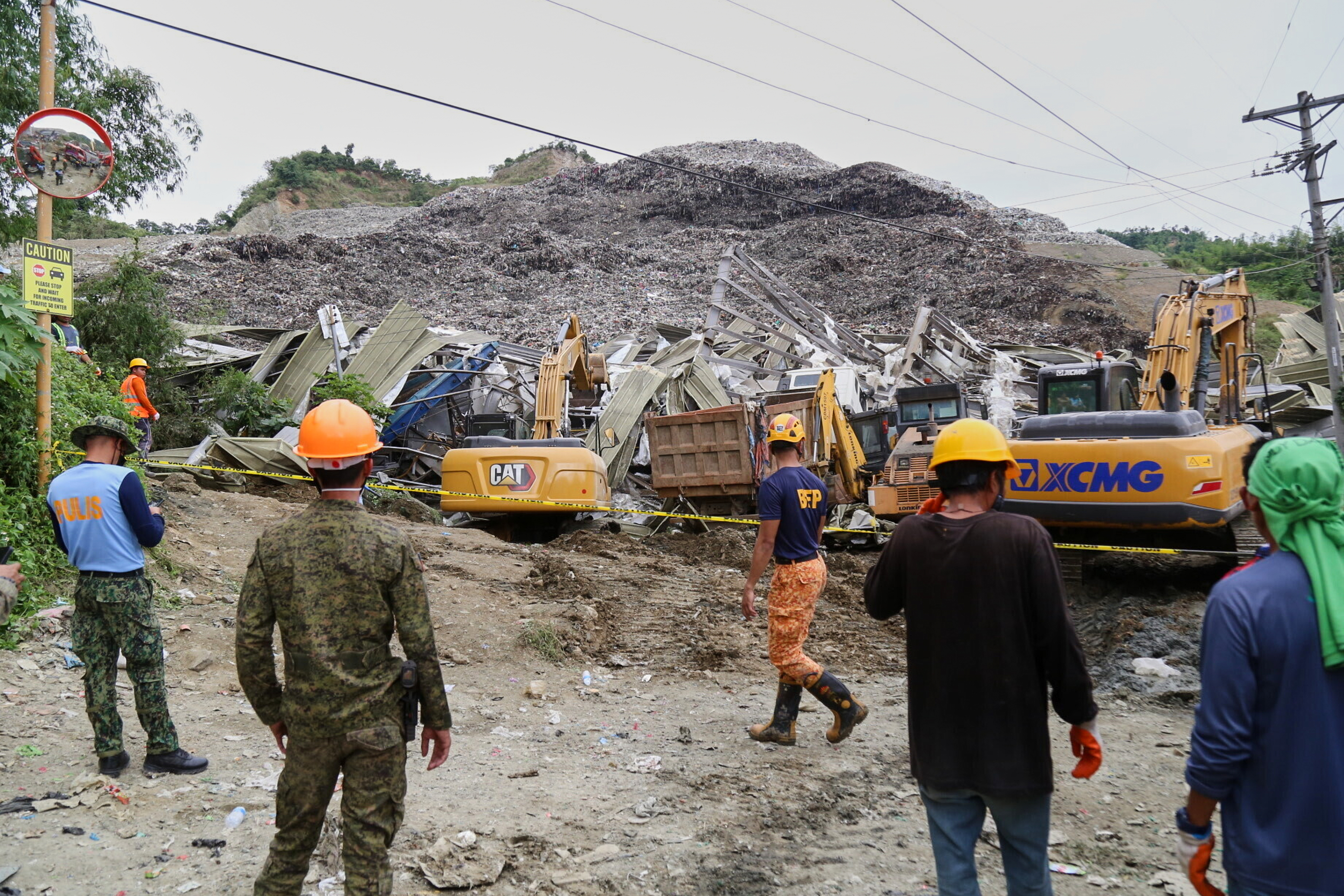 Rescue personnel work at the site of a huge mound of rubbish that collapsed.