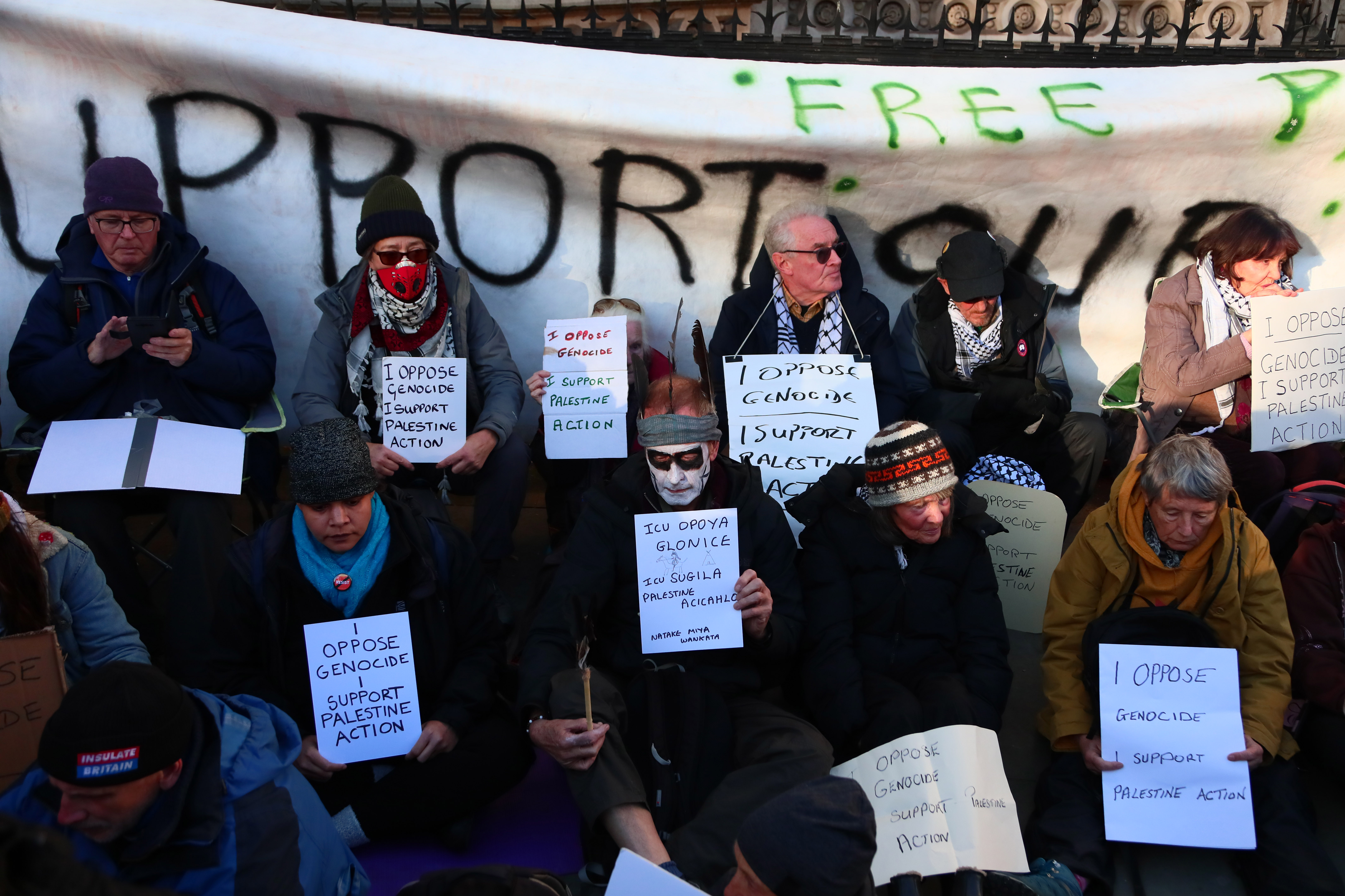 LONDON, ENGLAND - NOVEMBER 26: Protesters gather outside The Royal Courts of Justice as the High Court hears a judicial review on the proscription of Palestine Action under the terrorism act on November 26, 2025 in London, United Kingdom. A three-day judicial review is being heard by the High Court on the proscription of Palestine Action (PA) as a terrorist group. PA co-founder Huda Ammori leads the challenge to the pro-Palestinian campaign group's proscription under the Terrorism Act 2000. Last month the Home Office lost an appeal to block the review, which was due to begin on November 25, but was postponed a day. The Home Office-imposed ban on membership or support of PA took effect on July 5, after activists from the pro-Palestinian group broke into RAF Brize Norton and spray-painted two Voyager aircraft. Since their proscription, more than 2,000 people have been arrested for allegedly showing support of PA, mostly while holding signs reading: "I oppose genocide, I support Palestine Action." (Photo by Alishia Abodunde/Getty Images)