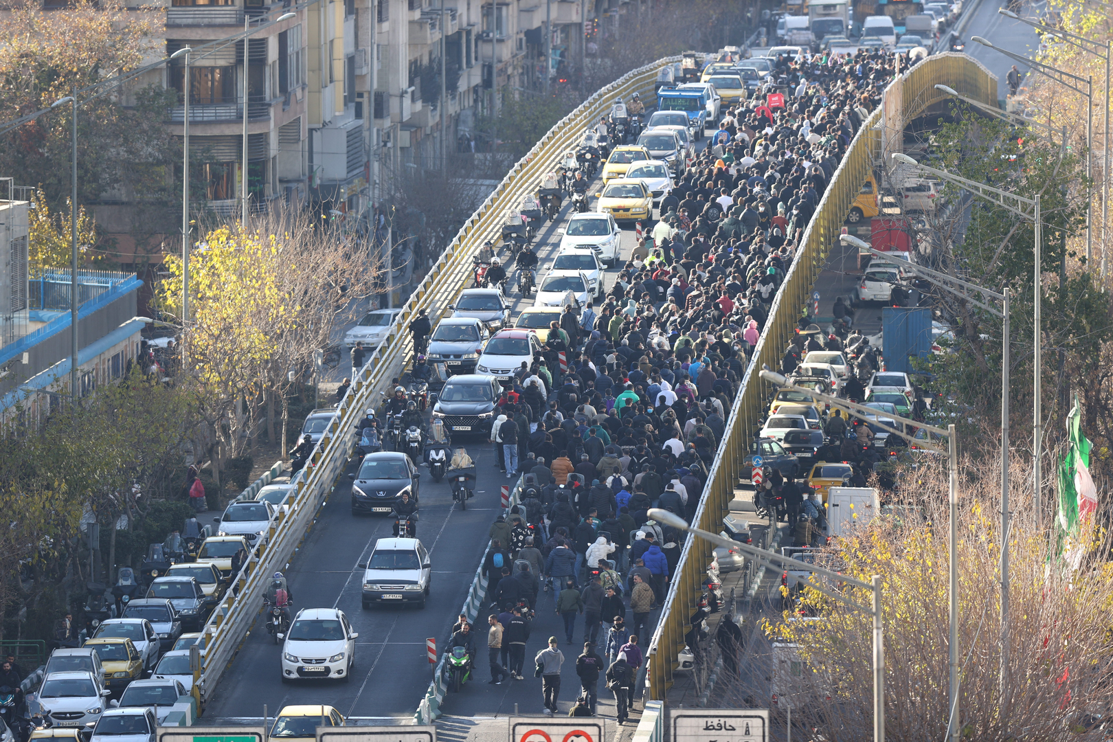 Shopkeepers and traders walk over a bridge during a protest against the economic conditions and Iran's embattled currency in Tehran on December 29, 2025. Some shopkeepers in Tehran closed their stores on December 29 in protest against economic hardships and sharp swings in Iran's embattled currency, Iranian media reported, following similar demonstrations a day earlier. Iran's currency has hit new lows on the unofficial market, with the US dollar trading at around 1.42 million rials on Sunday, compared to 820,000 rials a year ago and the euro nearing 1.7 million rials, according to price monitoring websites. [AFP/Fars News Agency]
