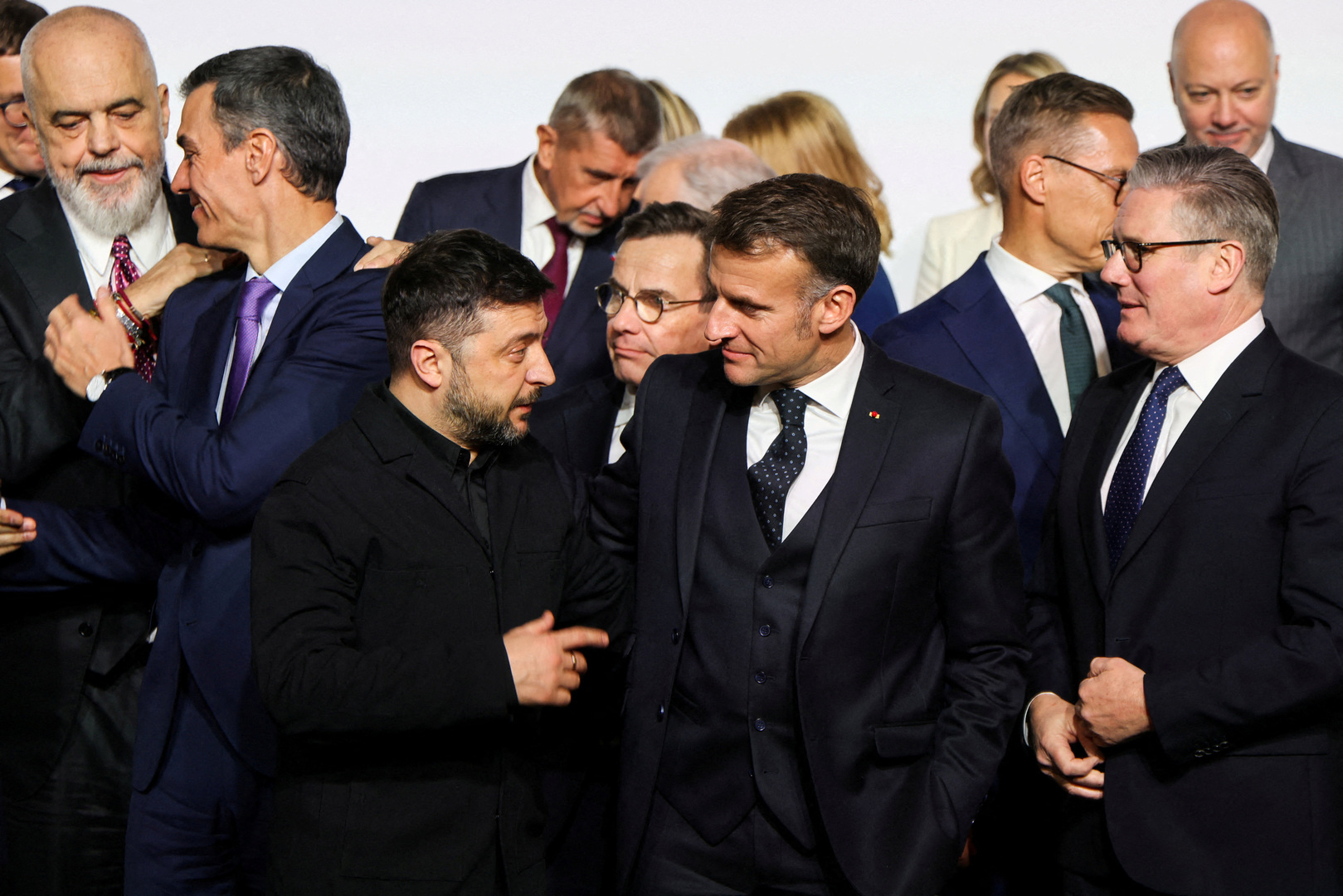 Ukraine's President Volodymyr Zelenskyy, France's President Emmanuel Macron and Britain's Prime Minister Keir Starmer react as they stand for a family photo, on the sideline of the so-called 'Coalition of the Willing' summit, at the Elysee Palace in Paris, France on Jan. 6, 2026. [Ludovic Marin/Reuters]