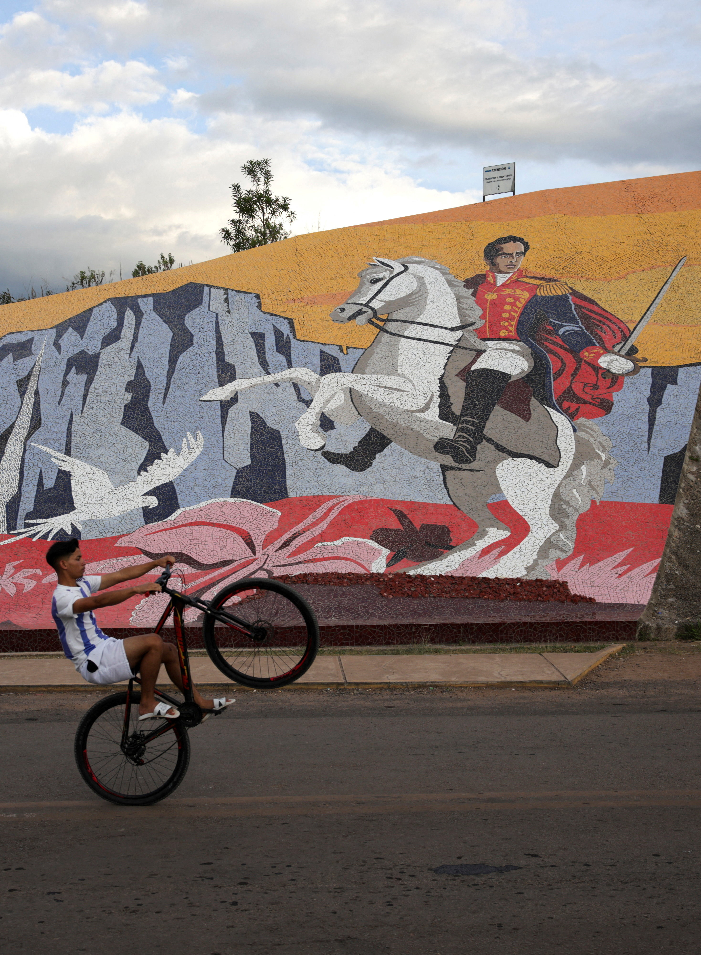A child rides a bike in front of a mural depicting independence hero Simon Bolivar at the border between Venezuela and Brazil, after the U.S. launched an attack on Venezuela, capturing its president, Nicolas Maduro, and his wife, Cilia Flores, in Pacaraima, Roraima, Brazil, January 5, 2026. REUTERS/Bruno Kelly