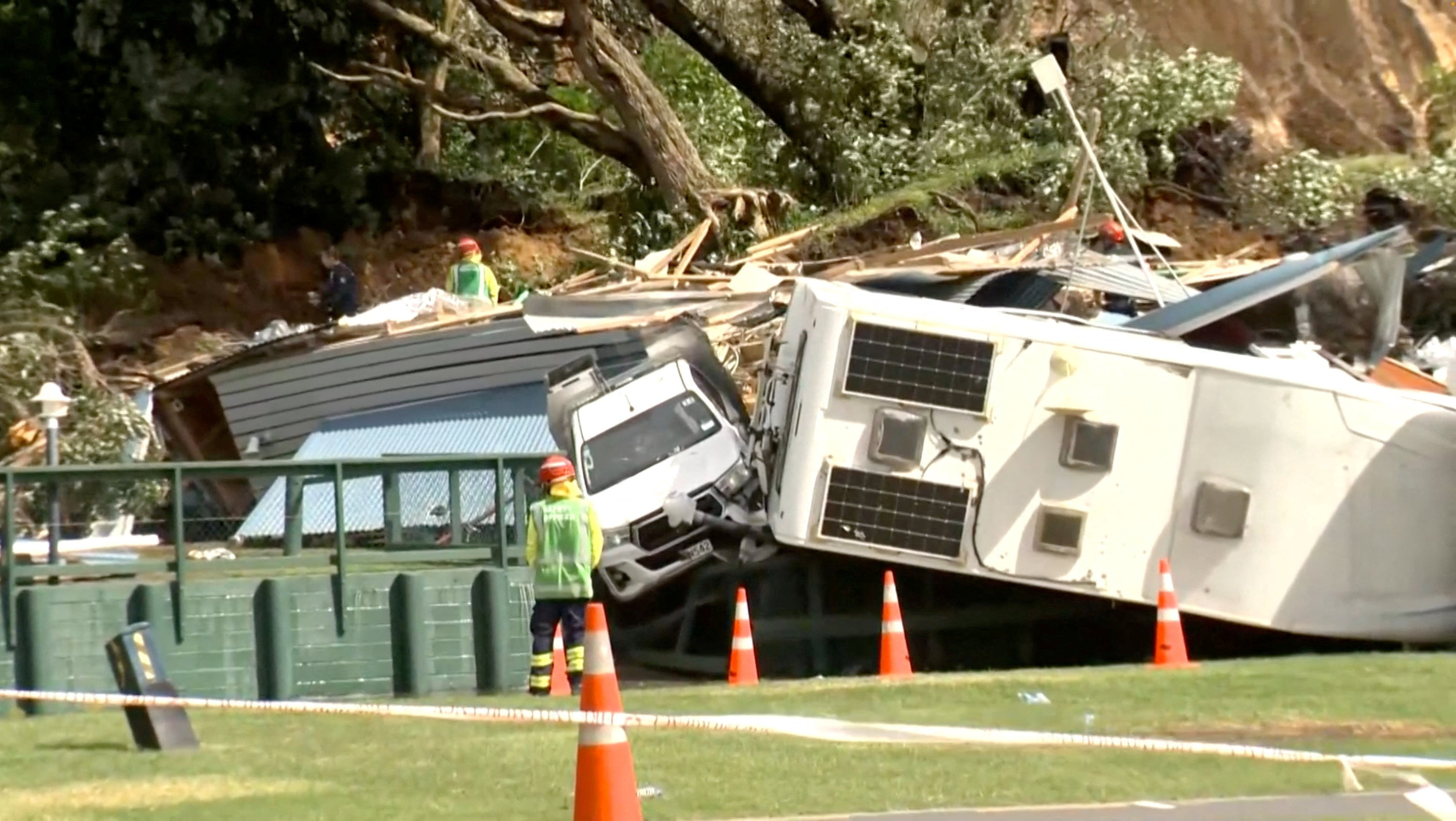 Damaged caravans and vehicles remain stuck amid rubble.