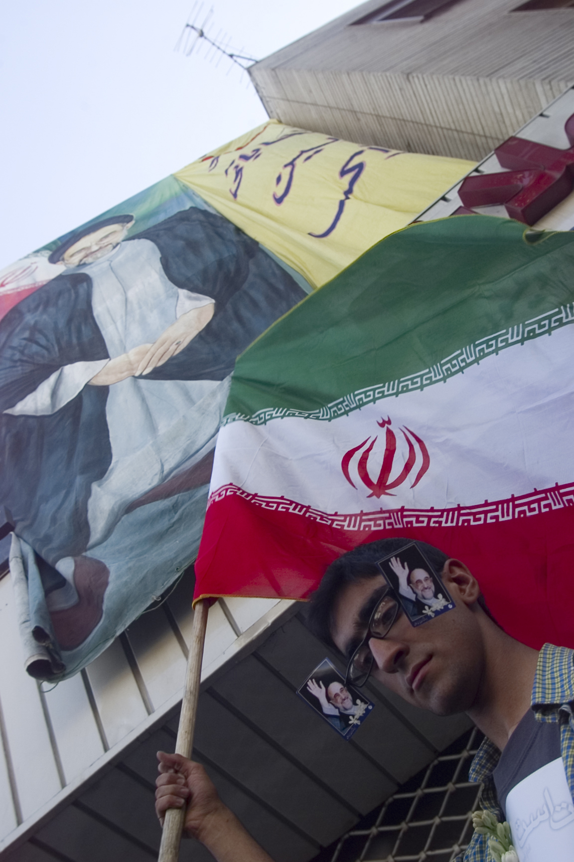 An Iranian with his glasses decorated with photos of President Mohammad Khatami carries national flag during celebration in central Tehran June 9, 2001, a day after country's presidential elections. As Iran's President Mohammad Khatami cruised towards re-election by a landslide on Saturday, supporters urged him to appoint a radical, reformist cabinet to overcome resistance to change by Islamic hardliners. REUTERS/Damir Sagolj (IRAN) BEST QUALITY AVAILABLE