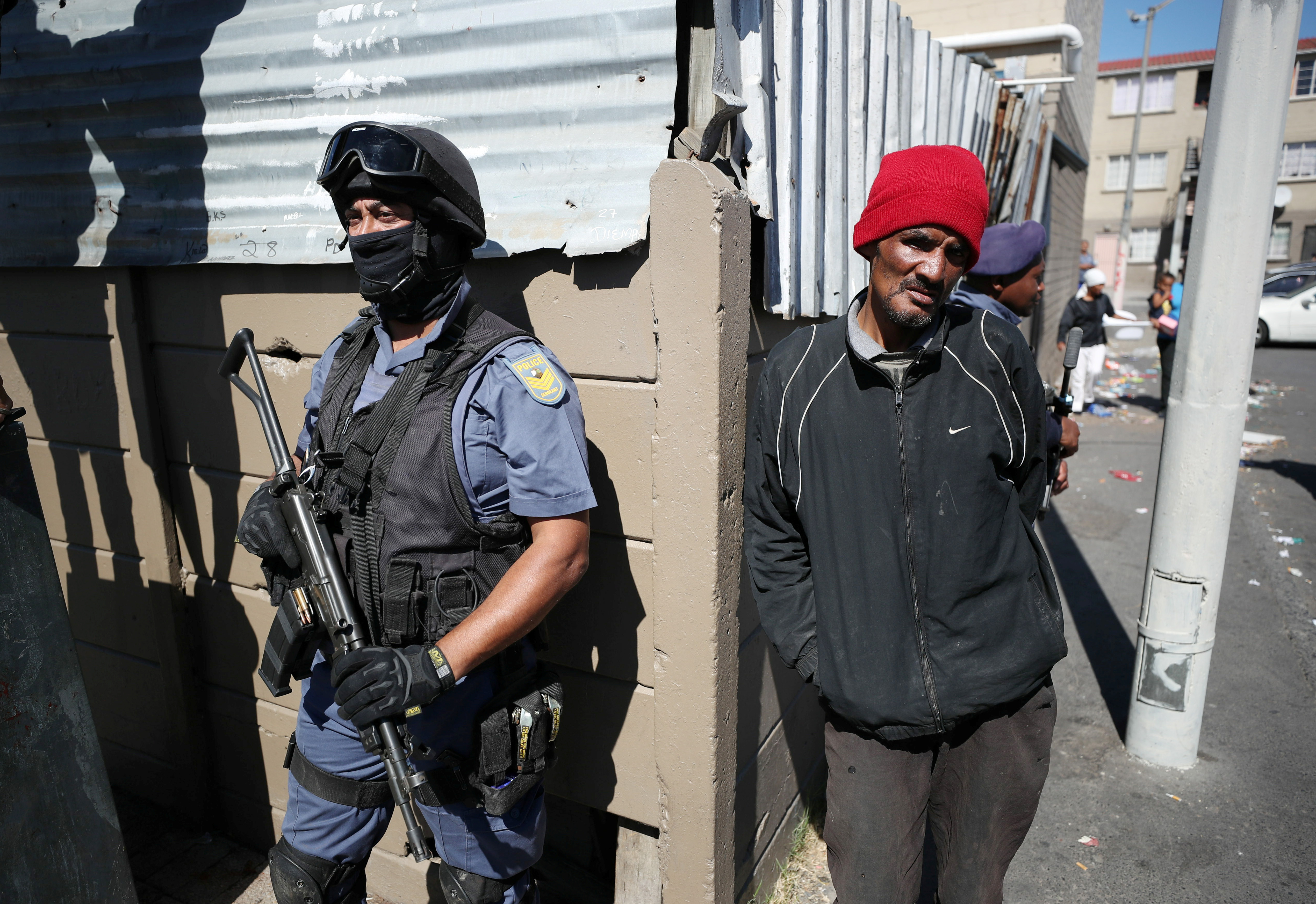 Residents look on as police stand guard while South African President Cyril Ramaphosa visits crime ridden Hanover Park to launch a new Anti-Gang Unit, in Cape Town, South Africa November 2, 2018. REUTERS/Mike Hutchings