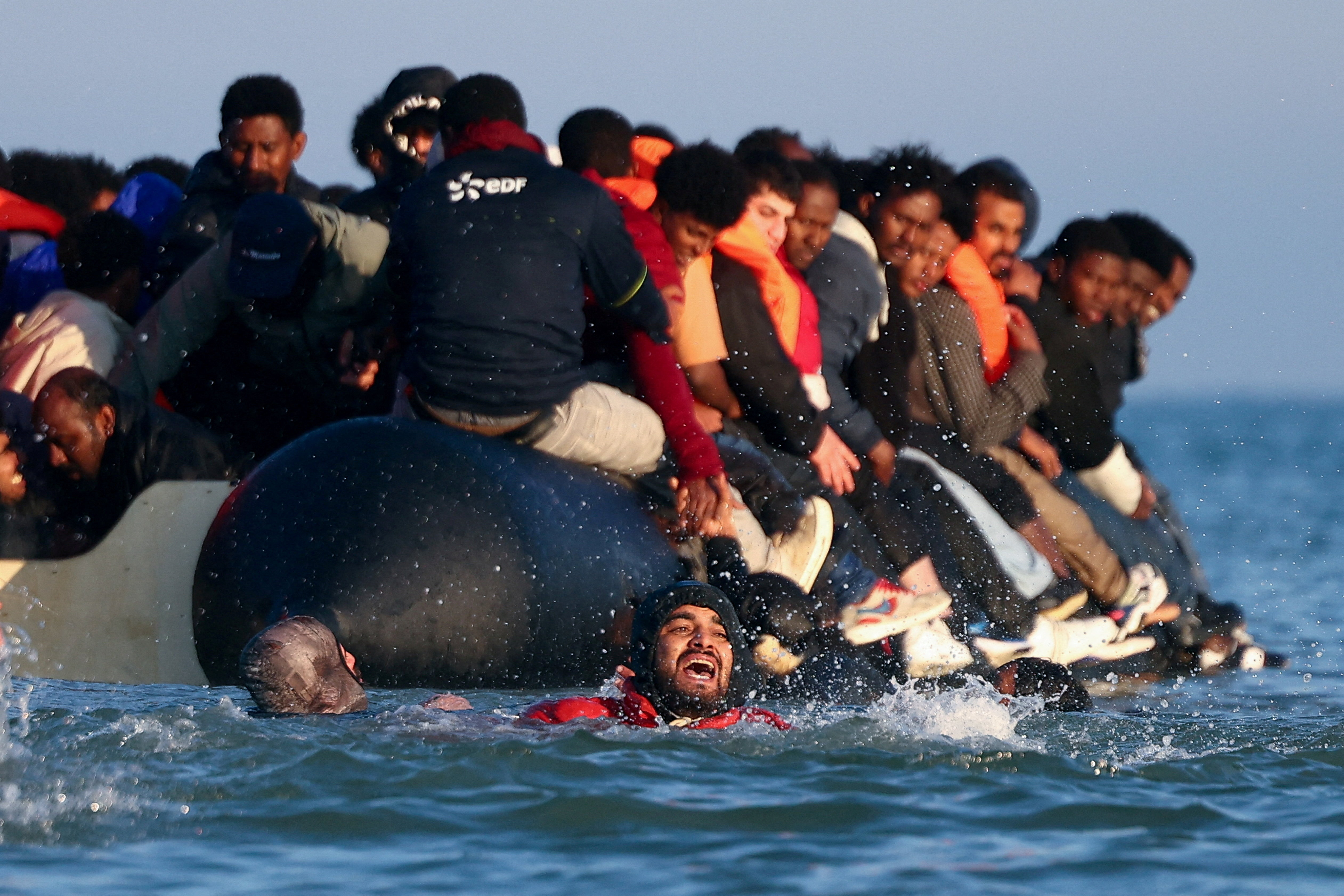 Migrants attempt to board an inflatable dinghy leaving the coast of northern France to cross the English Channel to reach Britain, from the beach of Petit-Fort-Philippe in Gravelines, near Calais, France, September 27, 2025. REUTERS/Abdul Saboor TPX IMAGES OF THE DAY