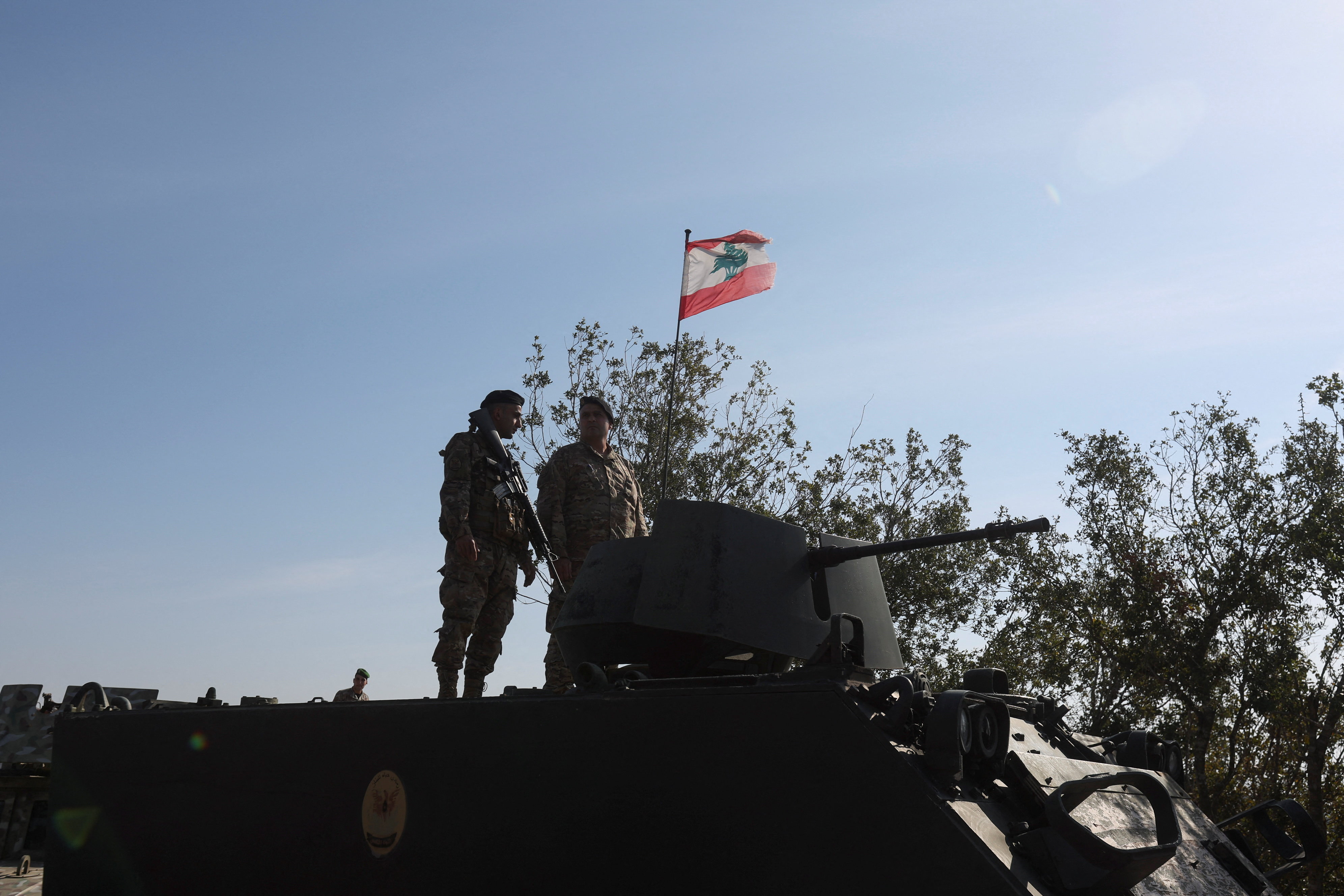 Lebanese army members stand on a military vehicle.
